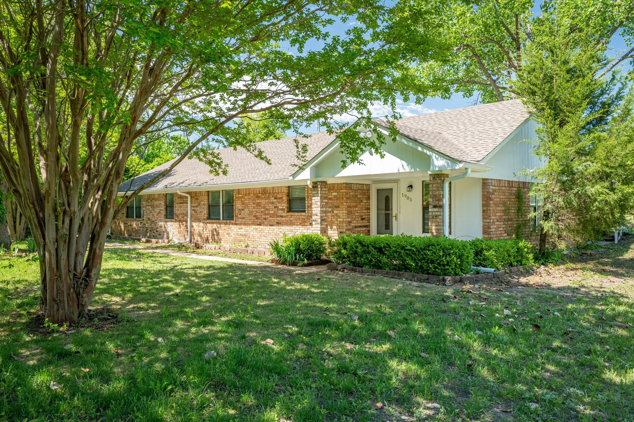 A classic brick façade, welcoming covered front porch, and established landscaping create a warm first impression.