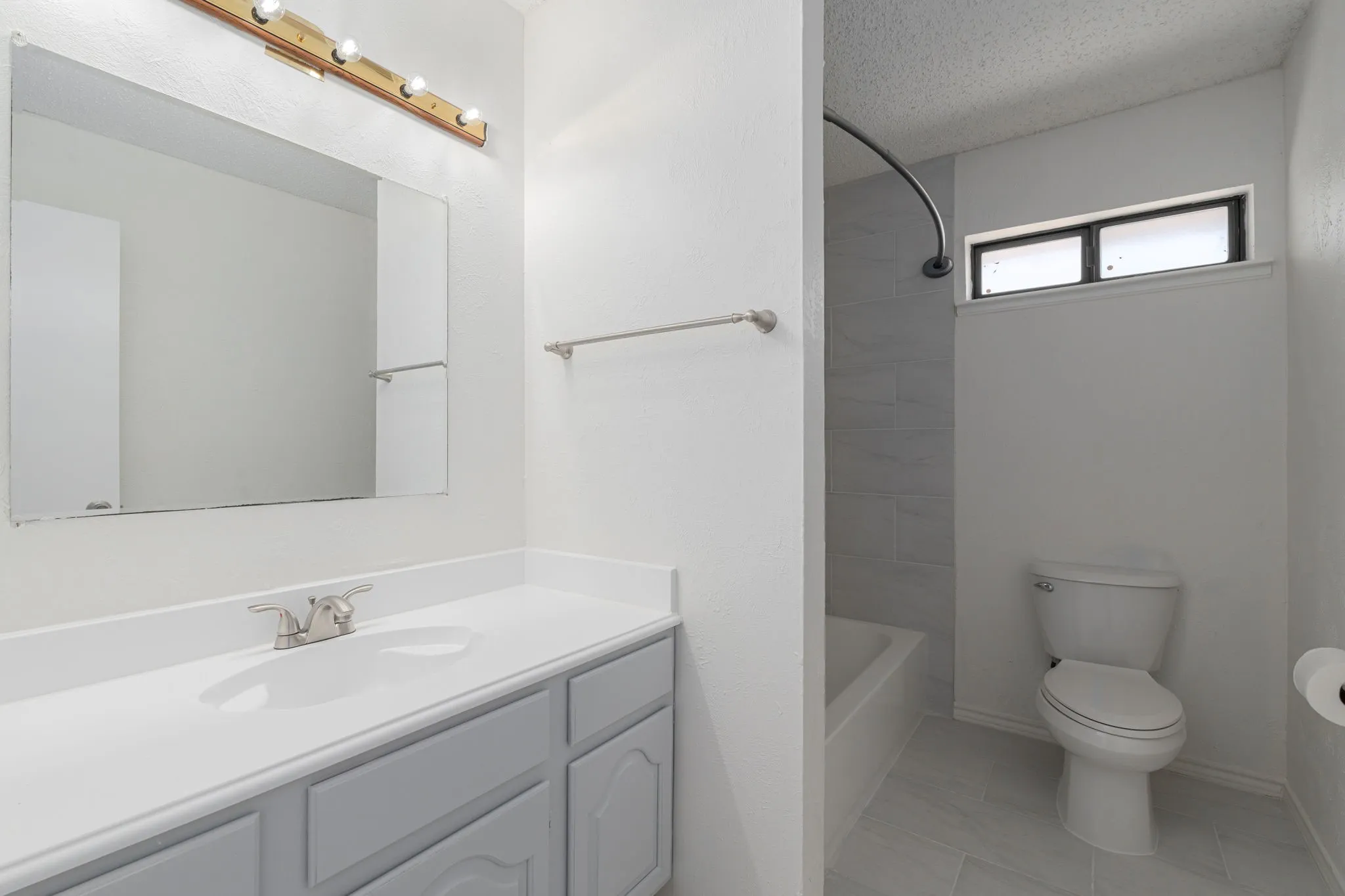 Beautifully renovated guest bath showcases a modern vanity, updated fixtures, and elegant tile surrounding the tub and shower.