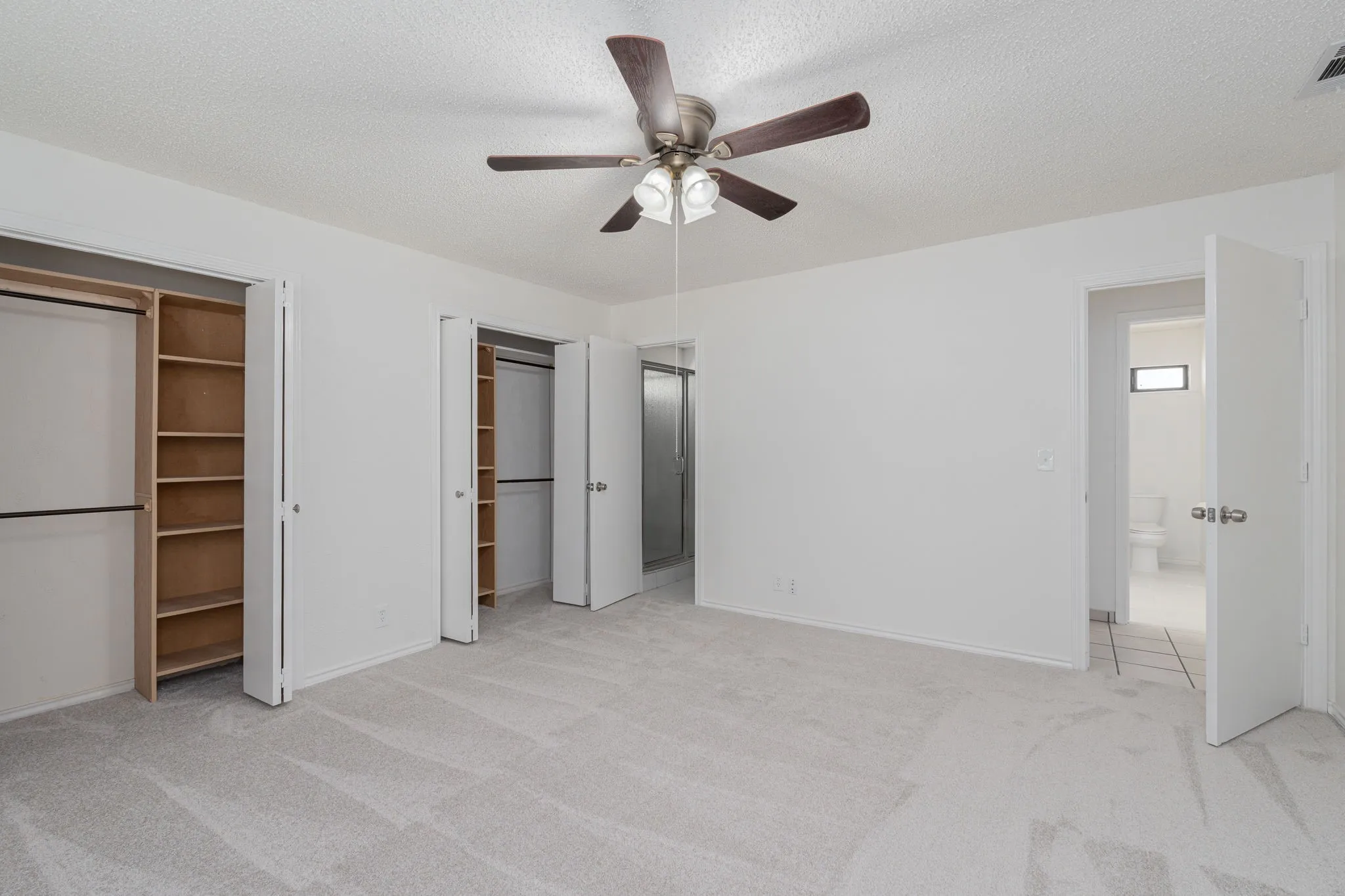Generously sized owner's retreat features dual closets, ceiling fan, and a peaceful atmosphere designed for comfort and relaxation.