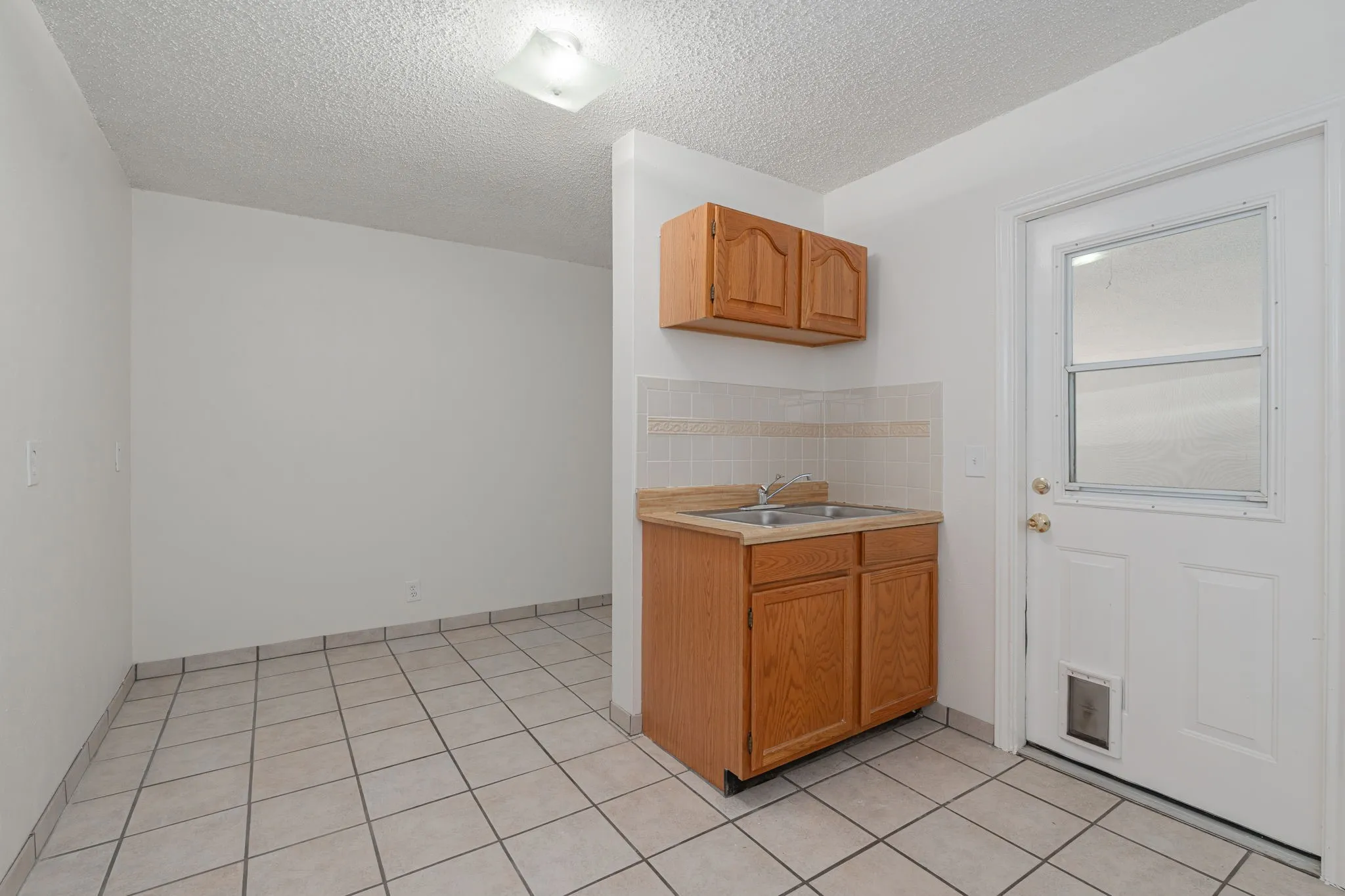 Spacious utility room with built-in sink, extra storage cabinetry, and exterior access makes everyday chores and outdoor living exceptionally convenient.