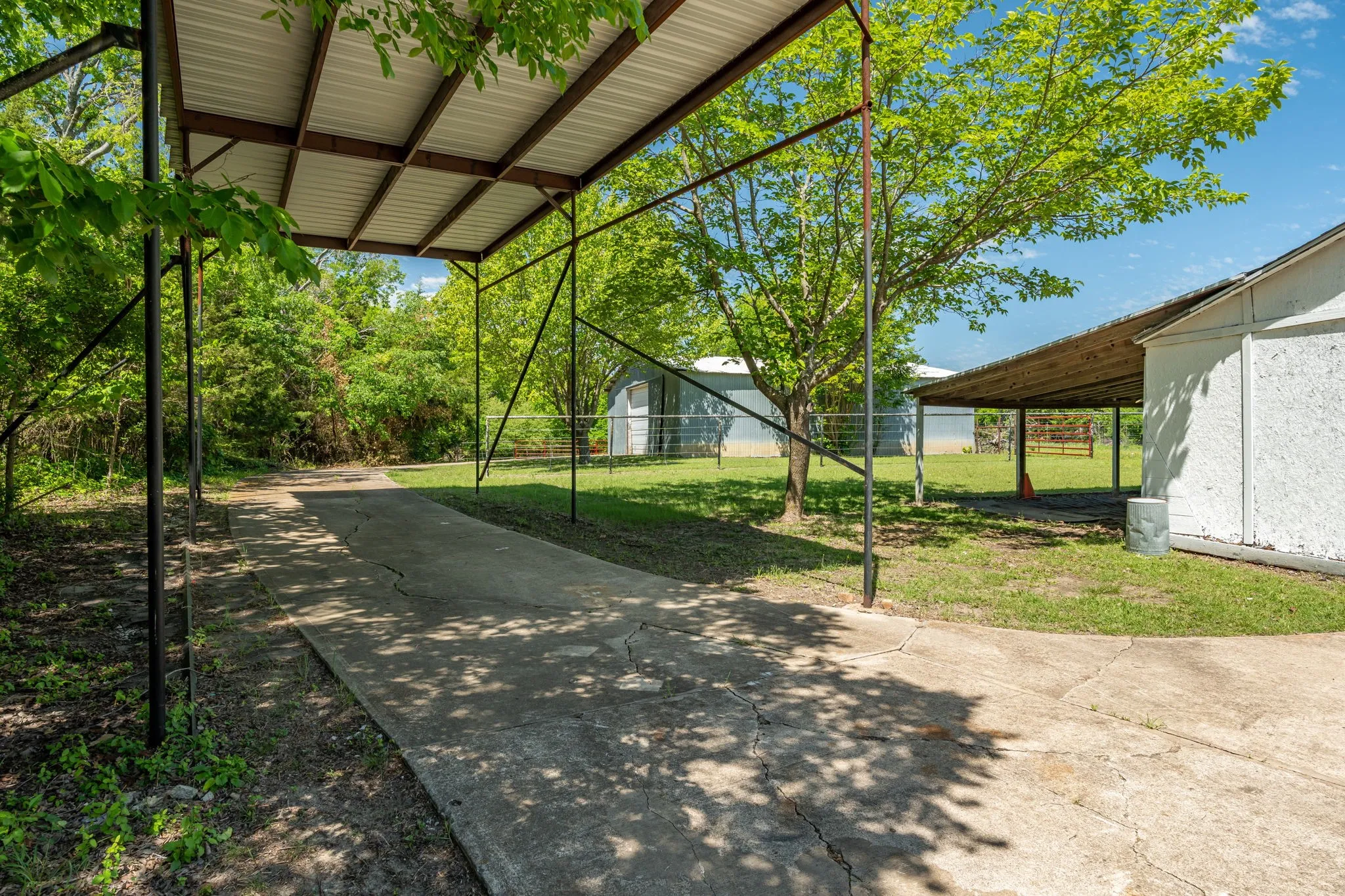 Additional covered parking leads to the workshop and outbuildings, ideal for RVs, trailers, or recreational vehicles.