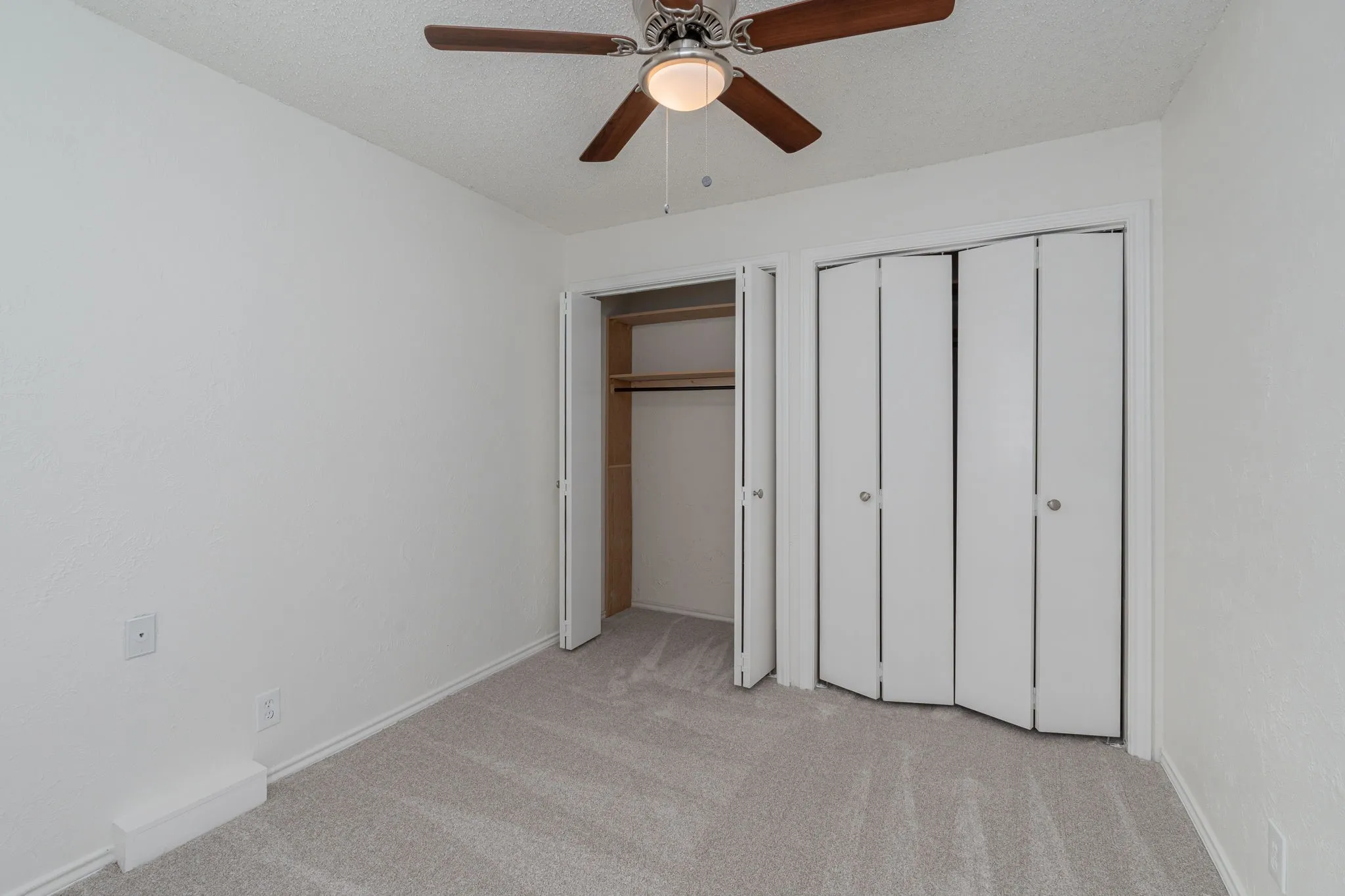 Bright guest bedroom features a ceiling fan, generous closet space, and a peaceful setting.