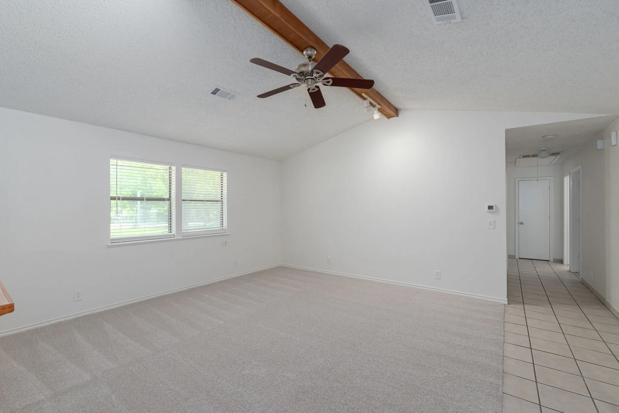 Vaulted ceilings with exposed beam detail enhance this oversized family room, perfect for relaxing or hosting guests.