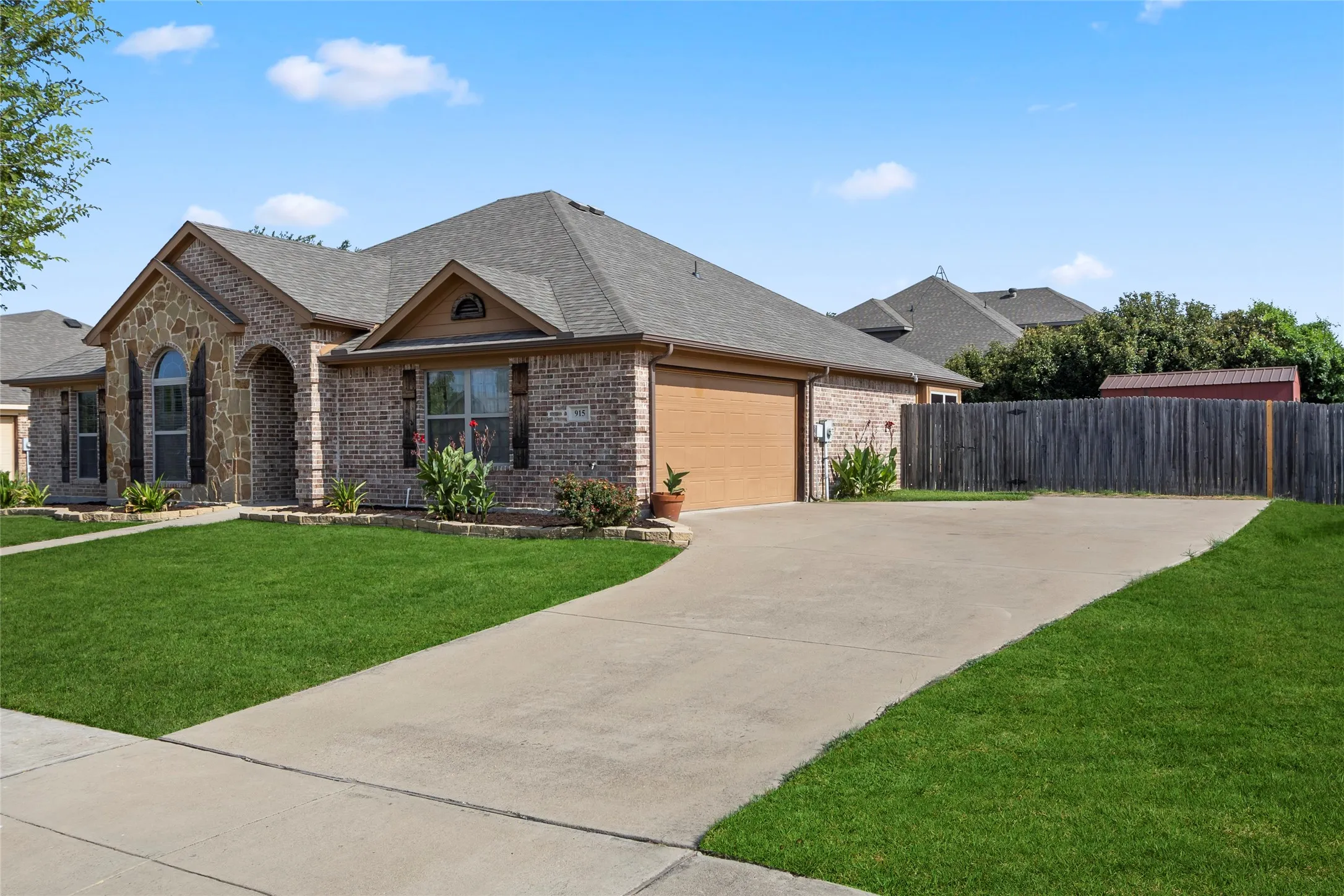 Brick and stone facade residence featuring an arched entryway, gabled rooflines, and a two-car garage with a wood-finish door