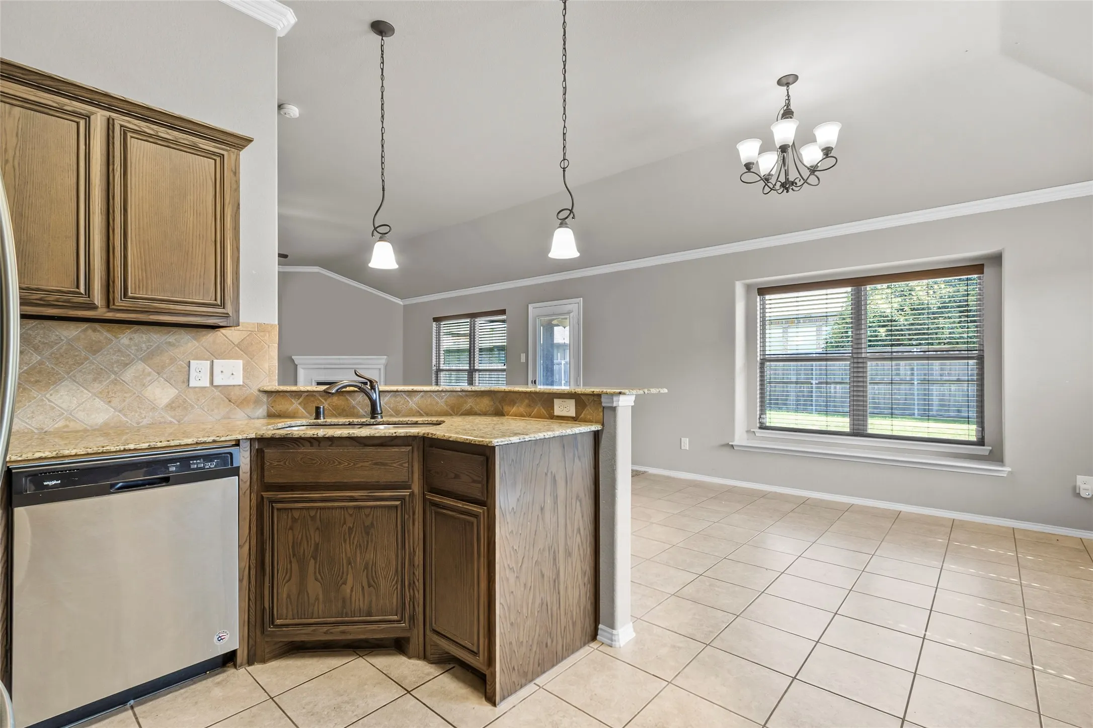 Kitchen featuring a stainless steel dishwasher, wood-finish cabinetry, granite countertops, and a stone tile backsplash