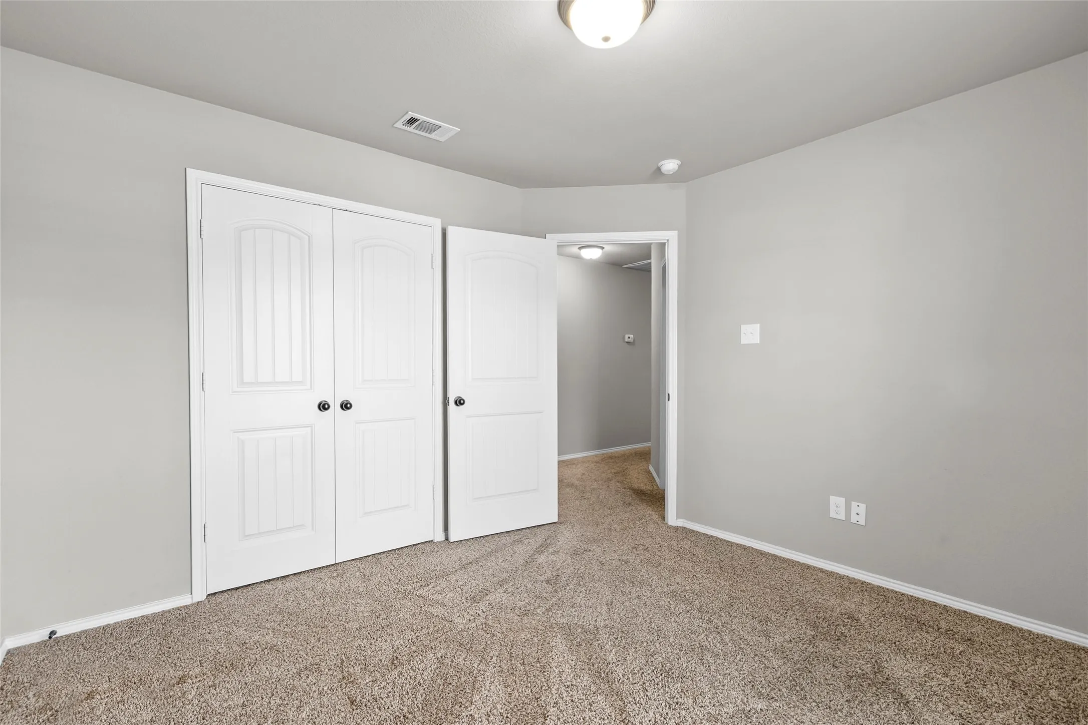 Bedroom featuring light gray walls, textured carpet flooring, and white trim