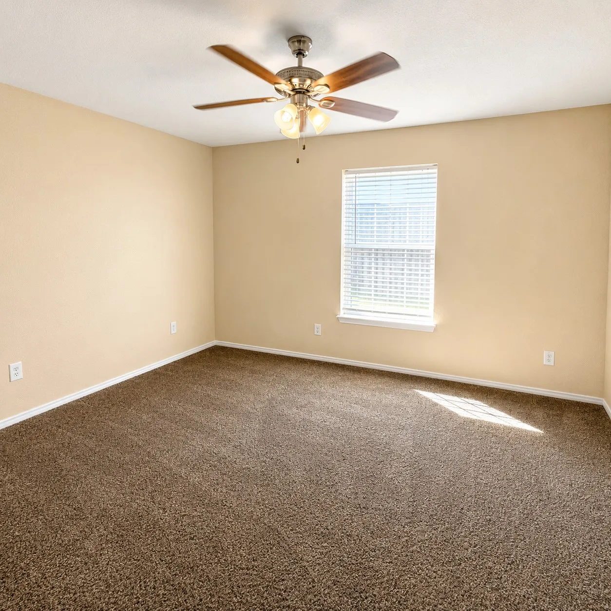 Bedroom featuring neutral tone walls, brown carpet flooring, and a ceiling fan with integrated lighting