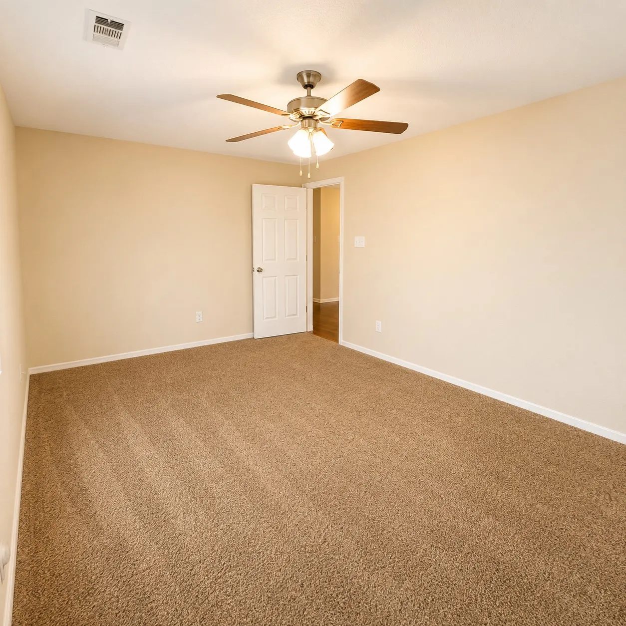Spacious room featuring neutral wall paint, brown carpet flooring, and a ceiling fan with integrated lighting