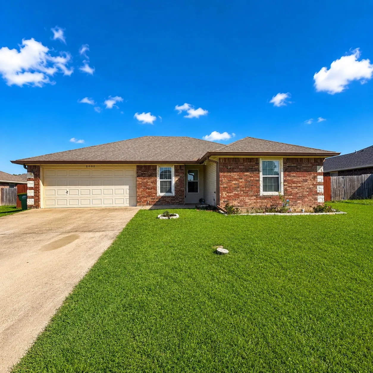 Brick facade residence with an attached two-car garage, concrete driveway, and a shingle roof