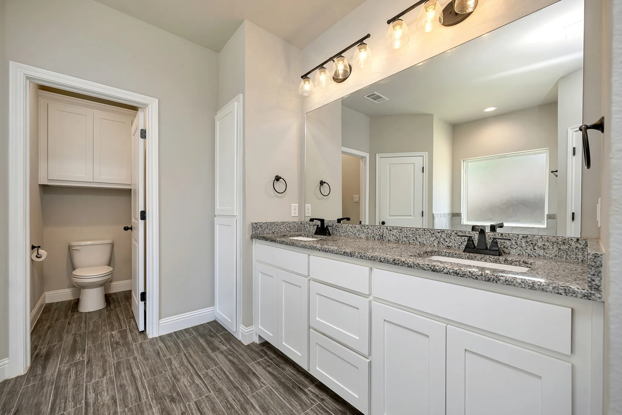 Beautiful wood look flooring and granite topped dual sink vanity.