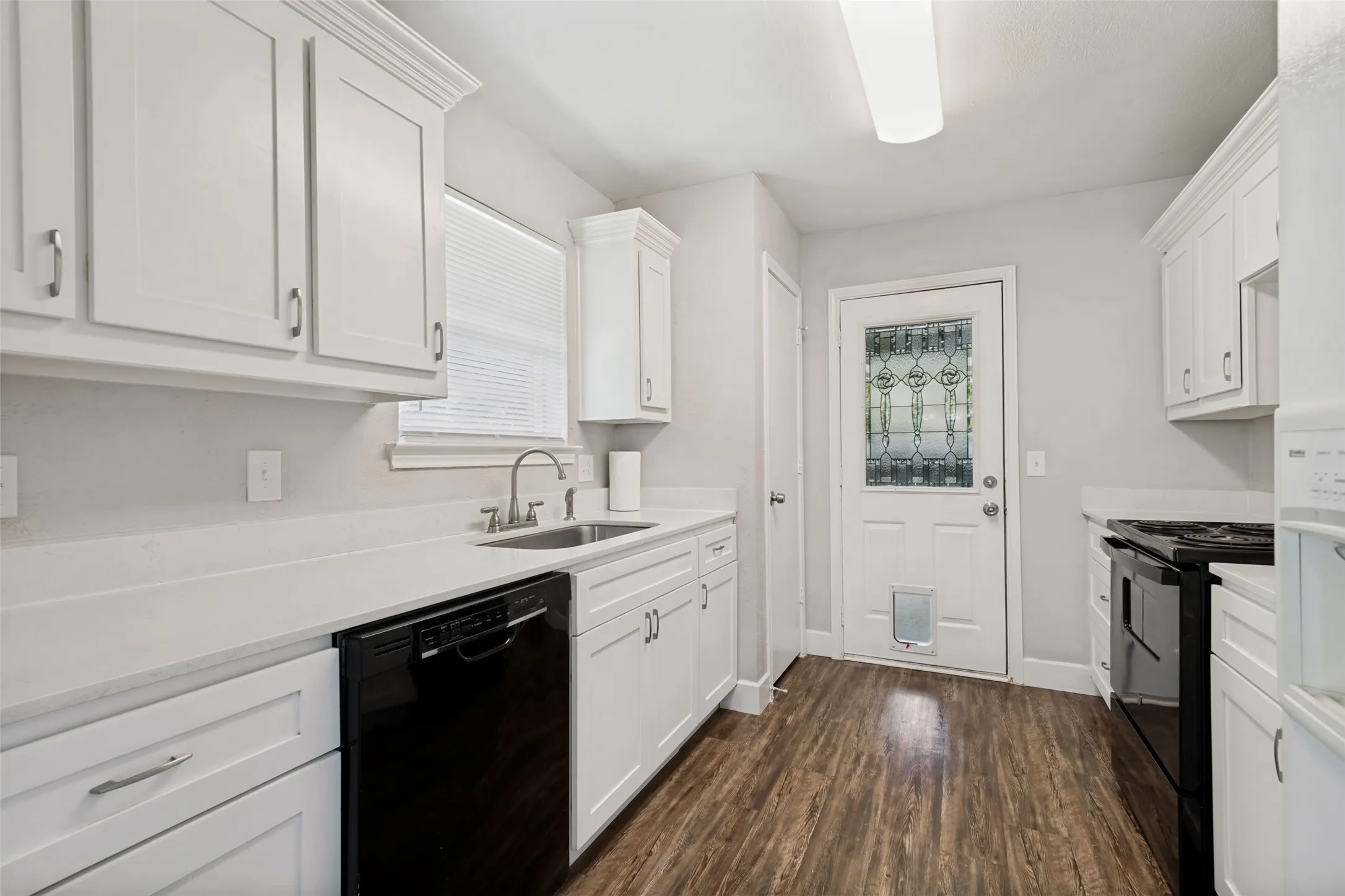Kitchen featuring wood-finish flooring, white cabinetry with silver hardware, and light-toned countertops