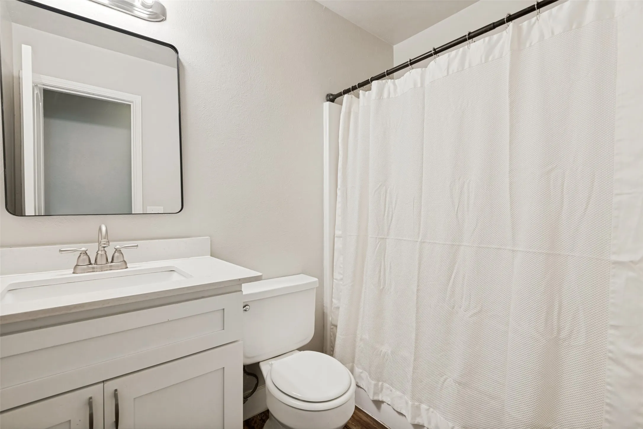 Bathroom featuring a white vanity with an integrated sink, brushed nickel faucet, and rectangular framed mirror