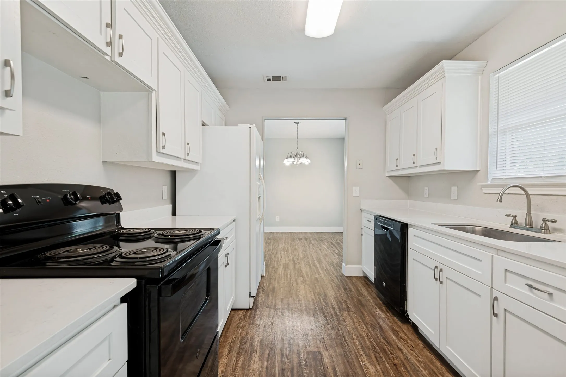 Kitchen featuring white cabinetry, light countertops, wood-finish flooring, a black range, and a stainless steel sink with a gooseneck faucet