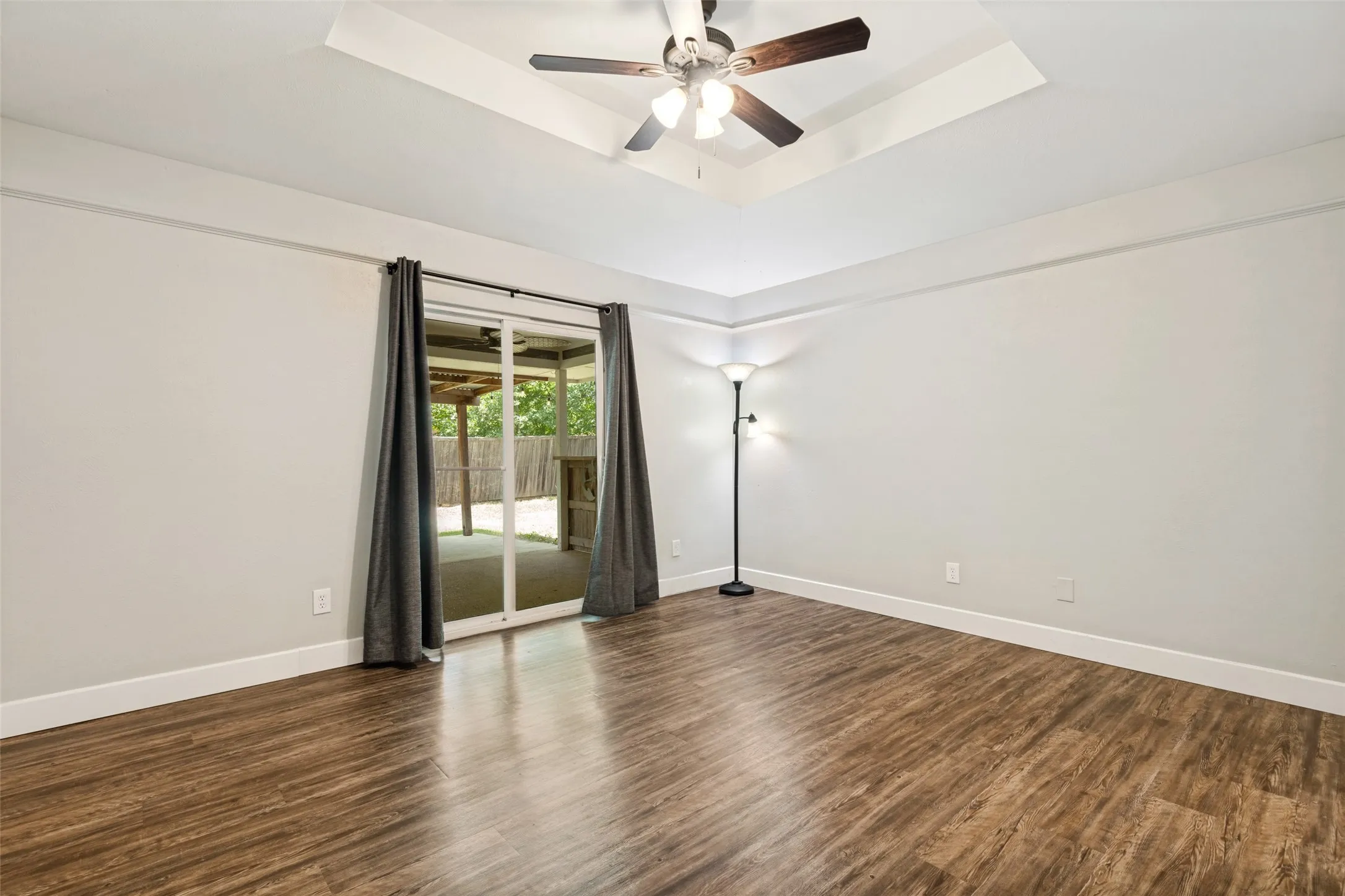Wood-finish flooring with white baseboards, complemented by light gray wall paint