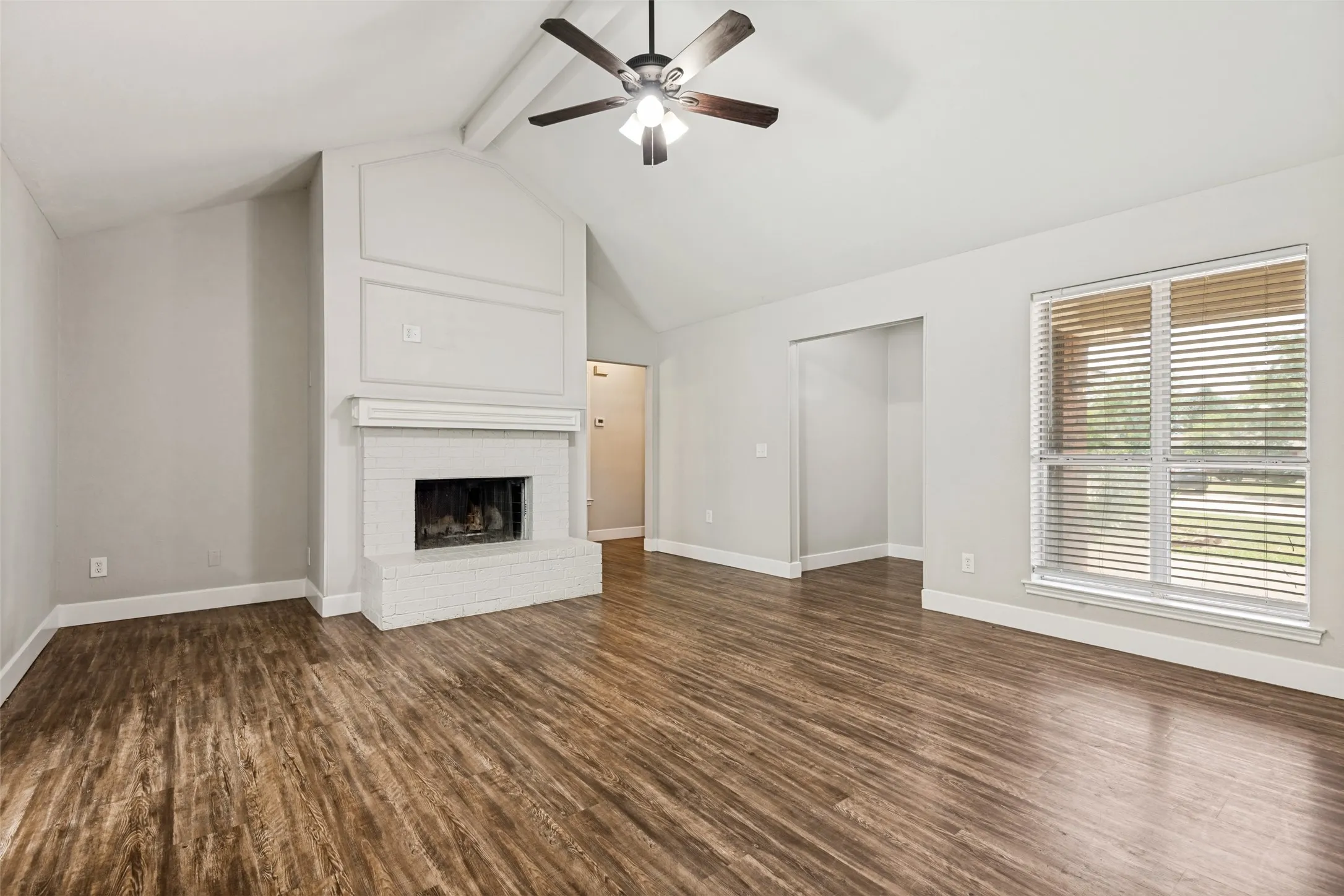 Living area featuring a vaulted ceiling and wood-finish flooring