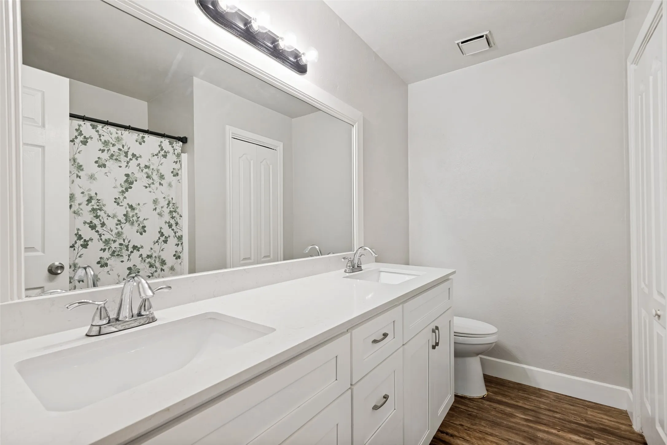 Dual vanity featuring white cabinetry with brushed nickel hardware, integrated sinks, and light-toned countertops