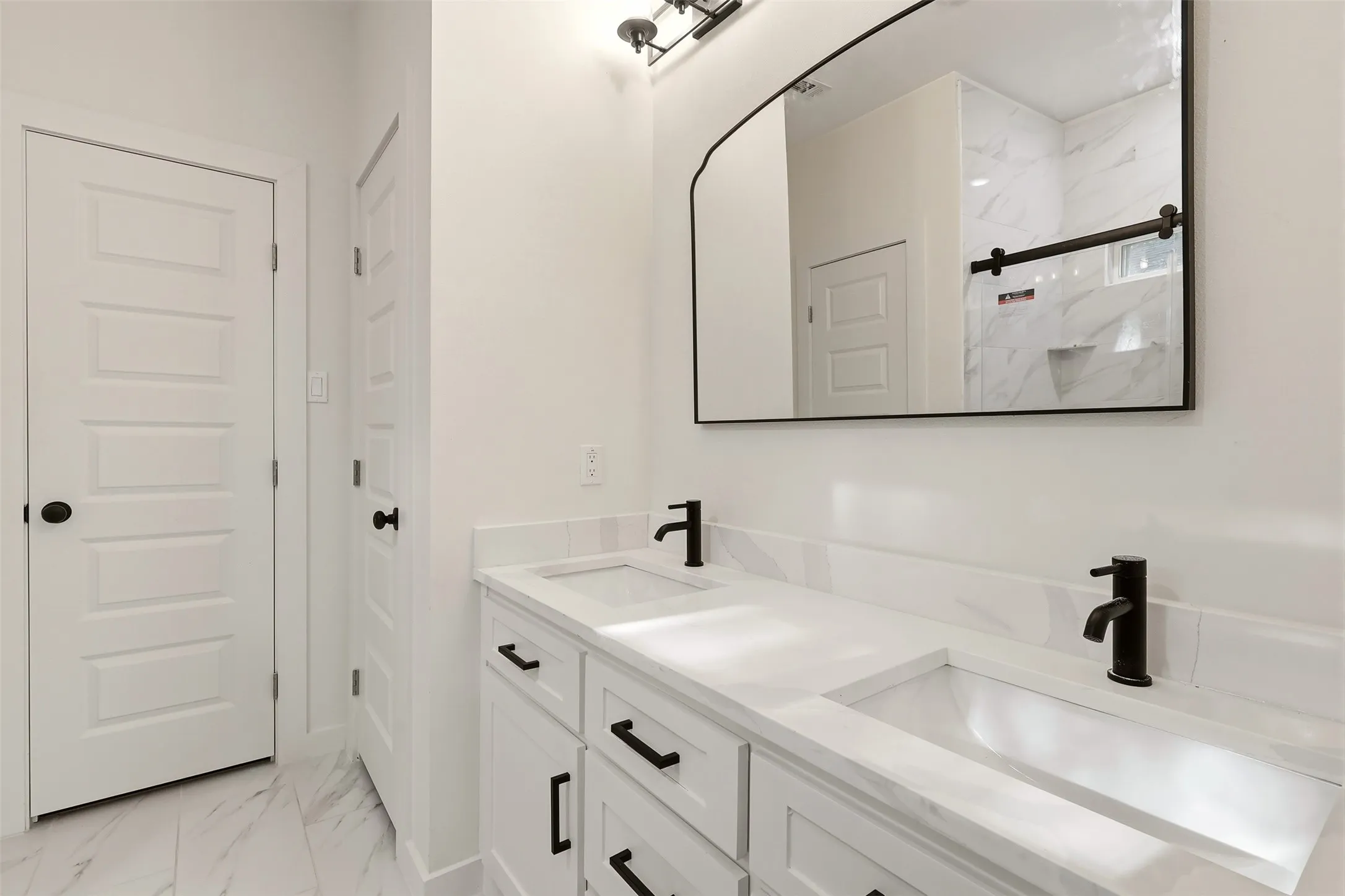 Double vanity with integrated sinks, white cabinetry, quartz countertops, and matte black fixtures