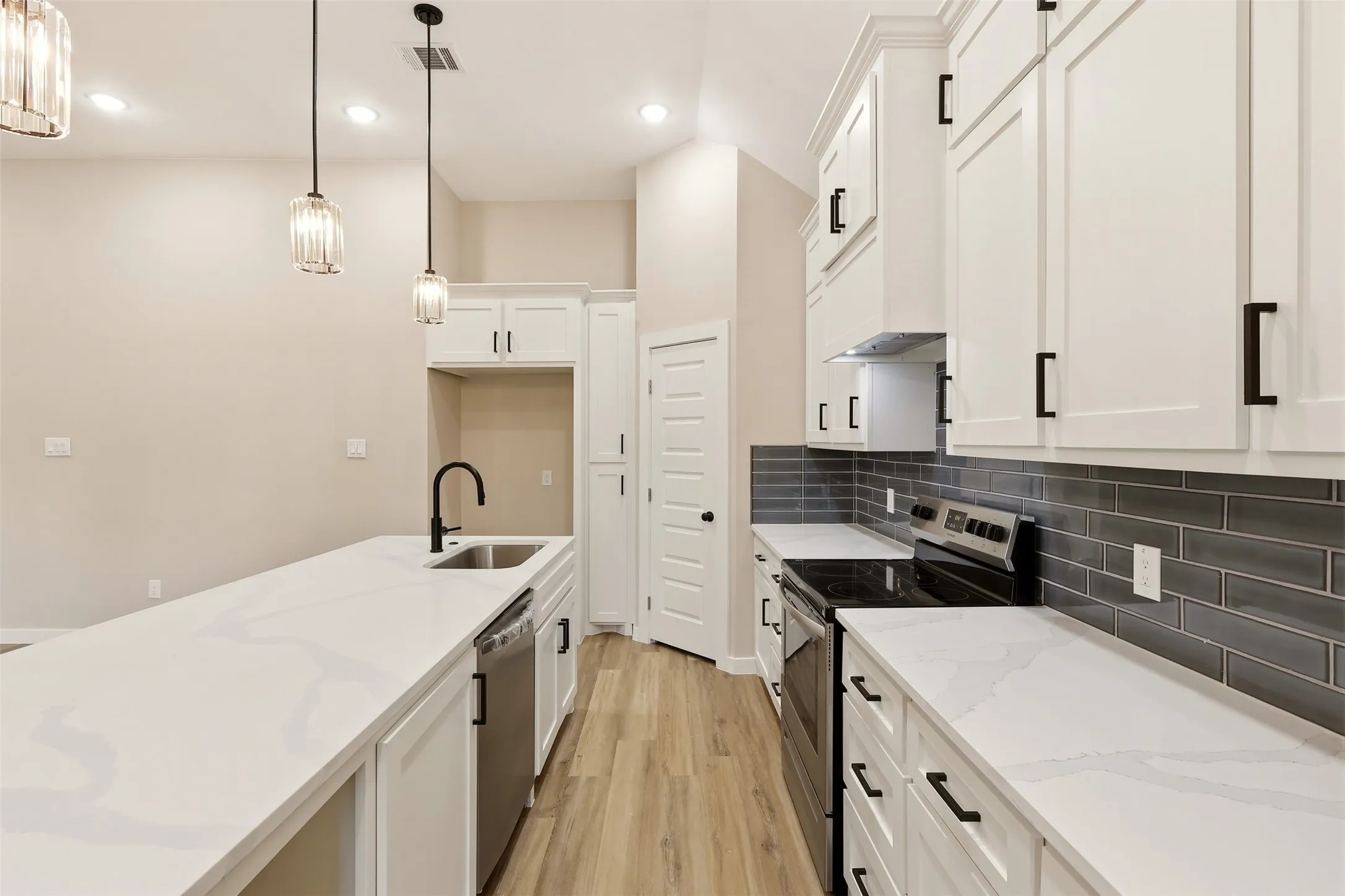 Modern kitchen featuring white shaker cabinetry and light-toned wood-finish flooring