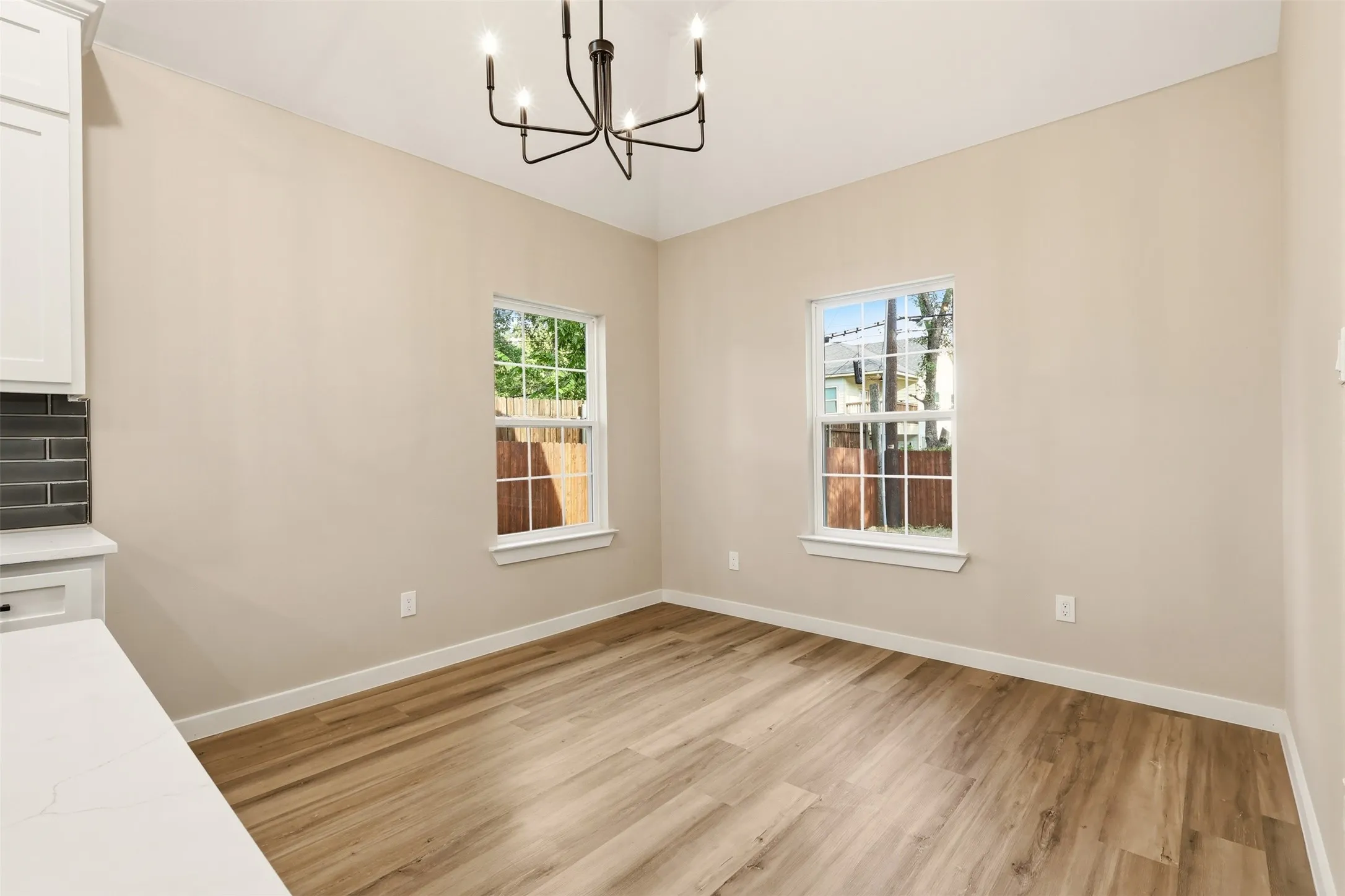 Open concept room featuring wood-finish flooring, white baseboards, and two windows