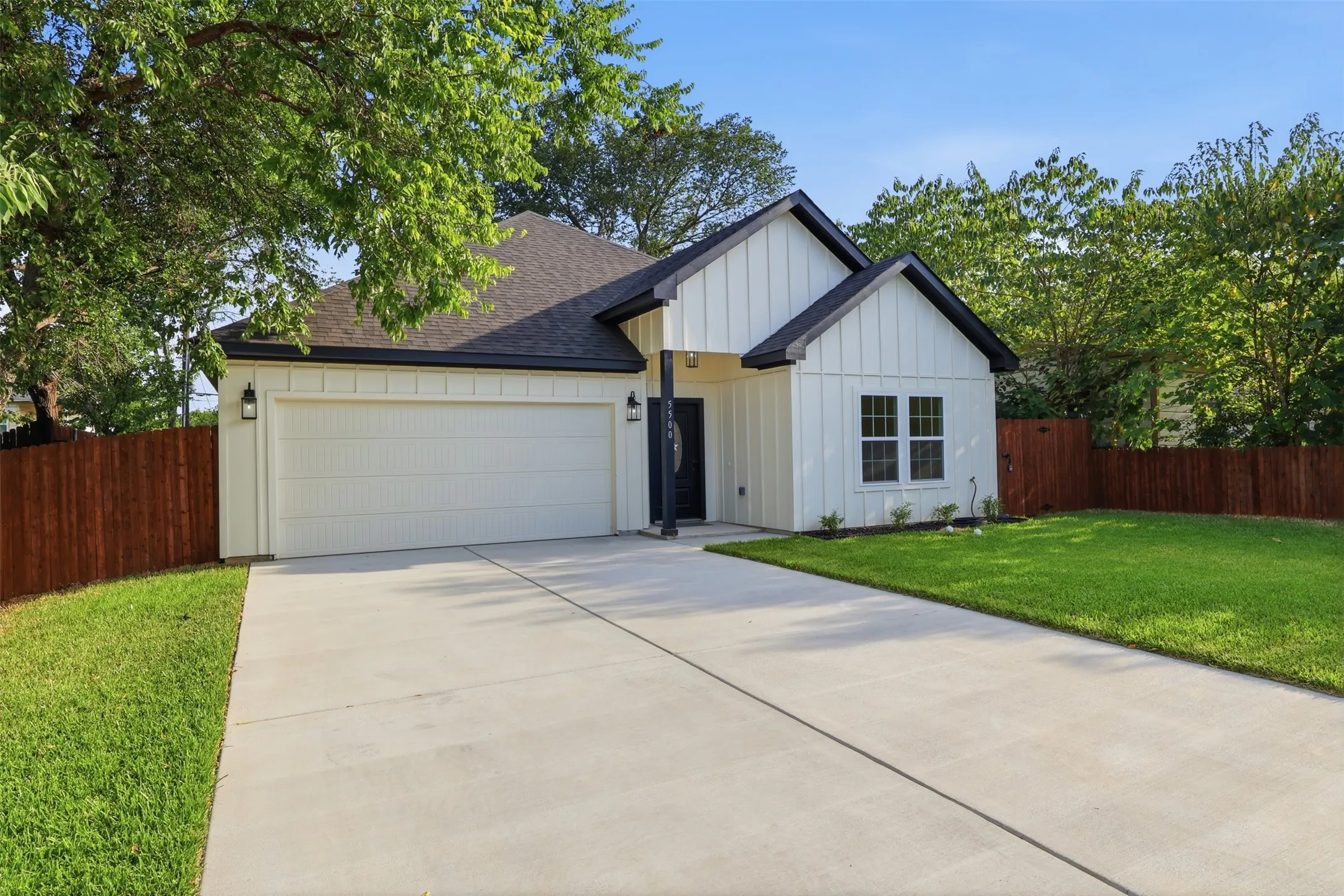 Modern farmhouse exterior featuring board and batten siding, dark trim accents, and a covered entry