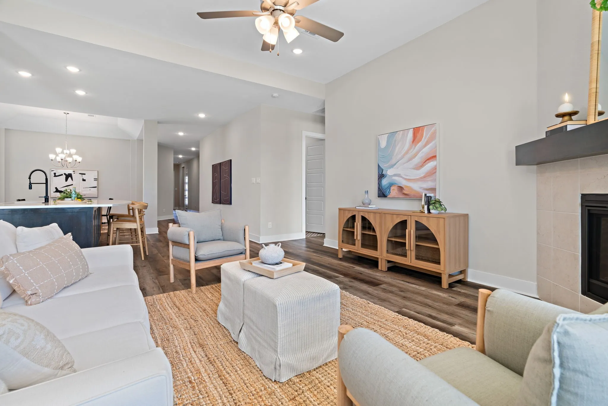 Living area featuring wood-finish flooring, a fireplace with a light-colored tile surround, and a dark mantel