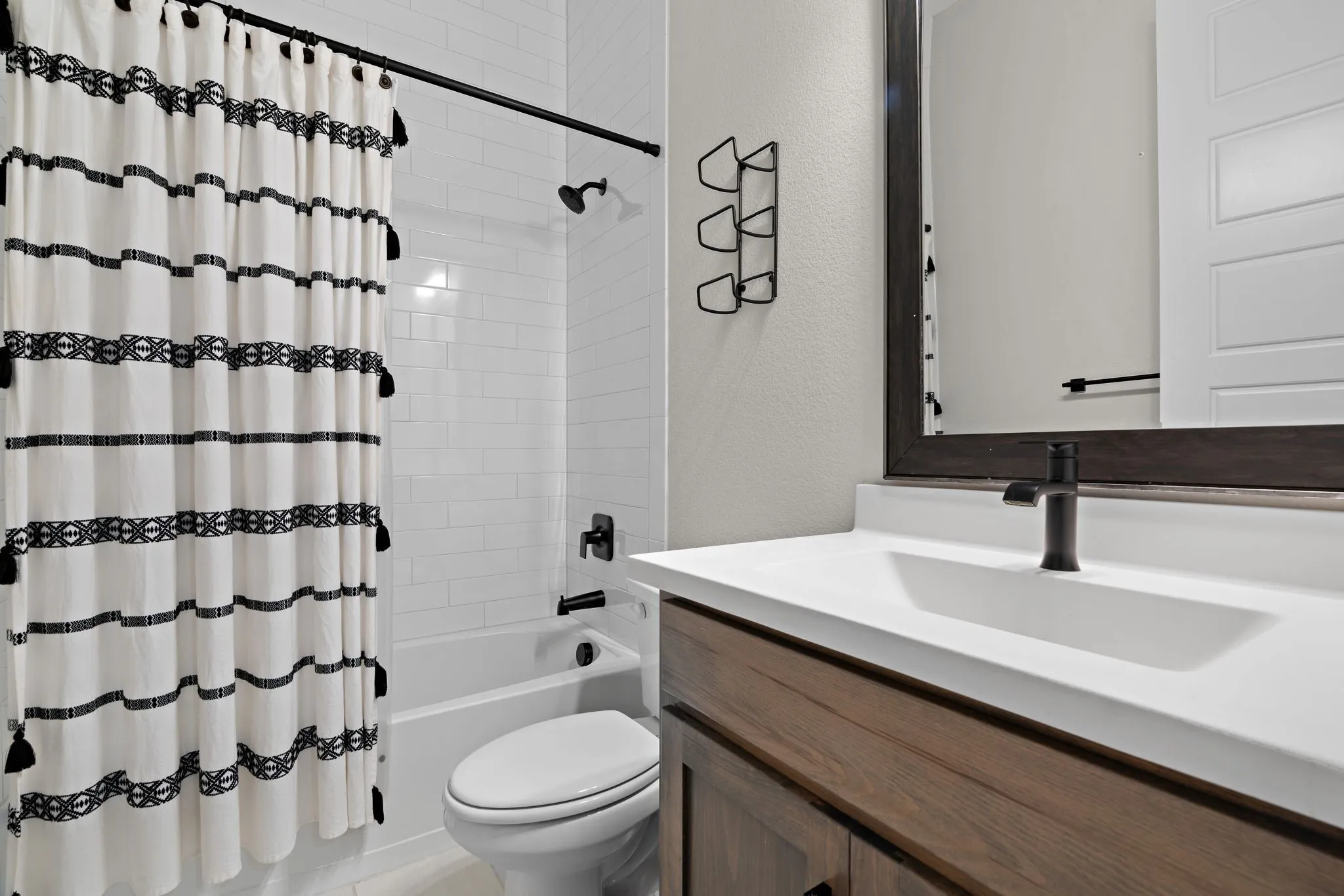 Bathroom featuring a white subway tile tub surround, dark wood-finish vanity with a white countertop, and a rectangular undermount sink