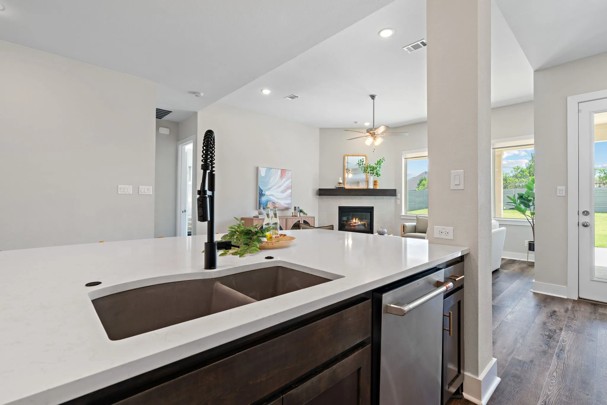 Kitchen island featuring a double basin sink with a matte black faucet, integrated dishwasher, and white solid surface countertop