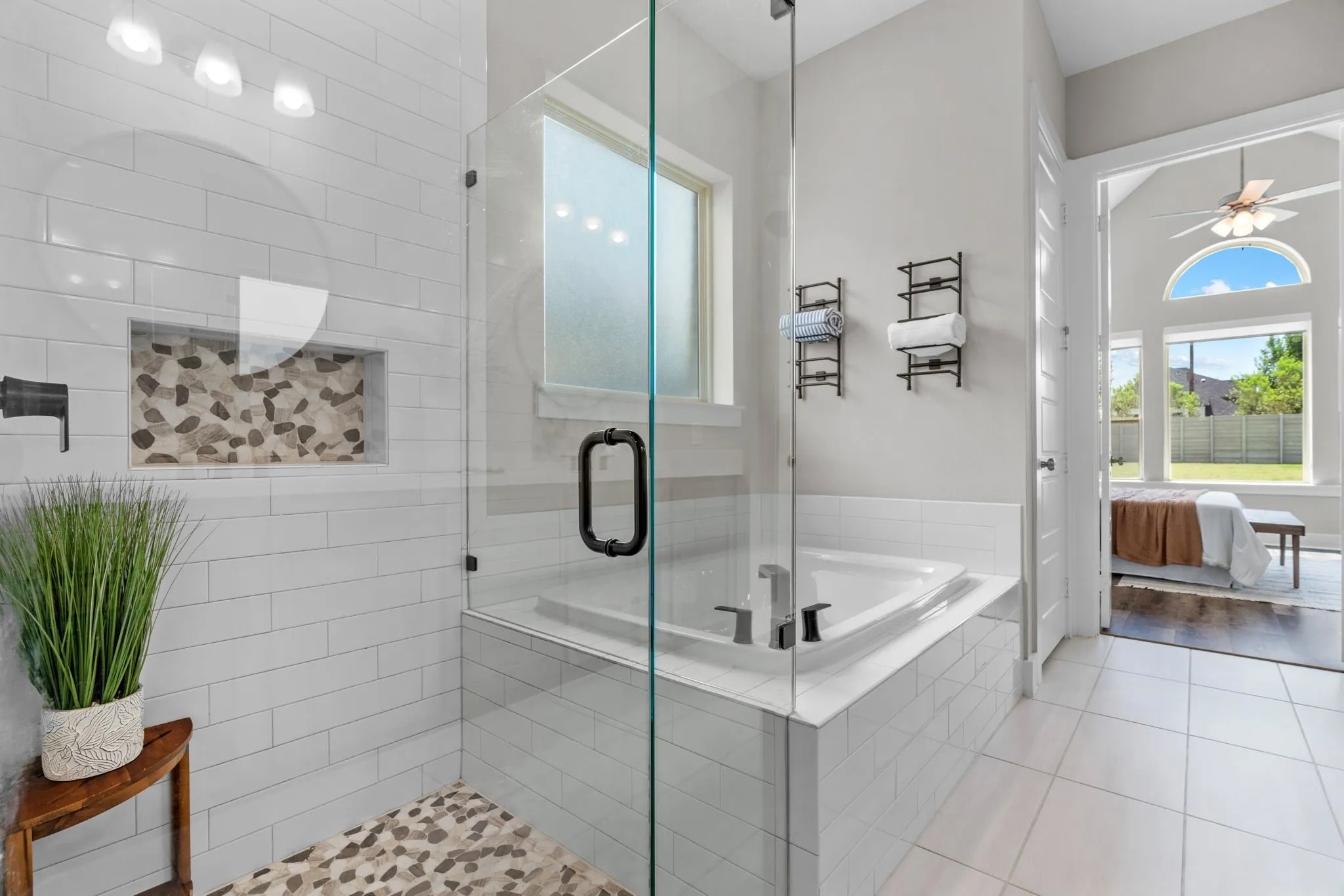 Glass-enclosed shower with pebble-tile floor and recessed shelf