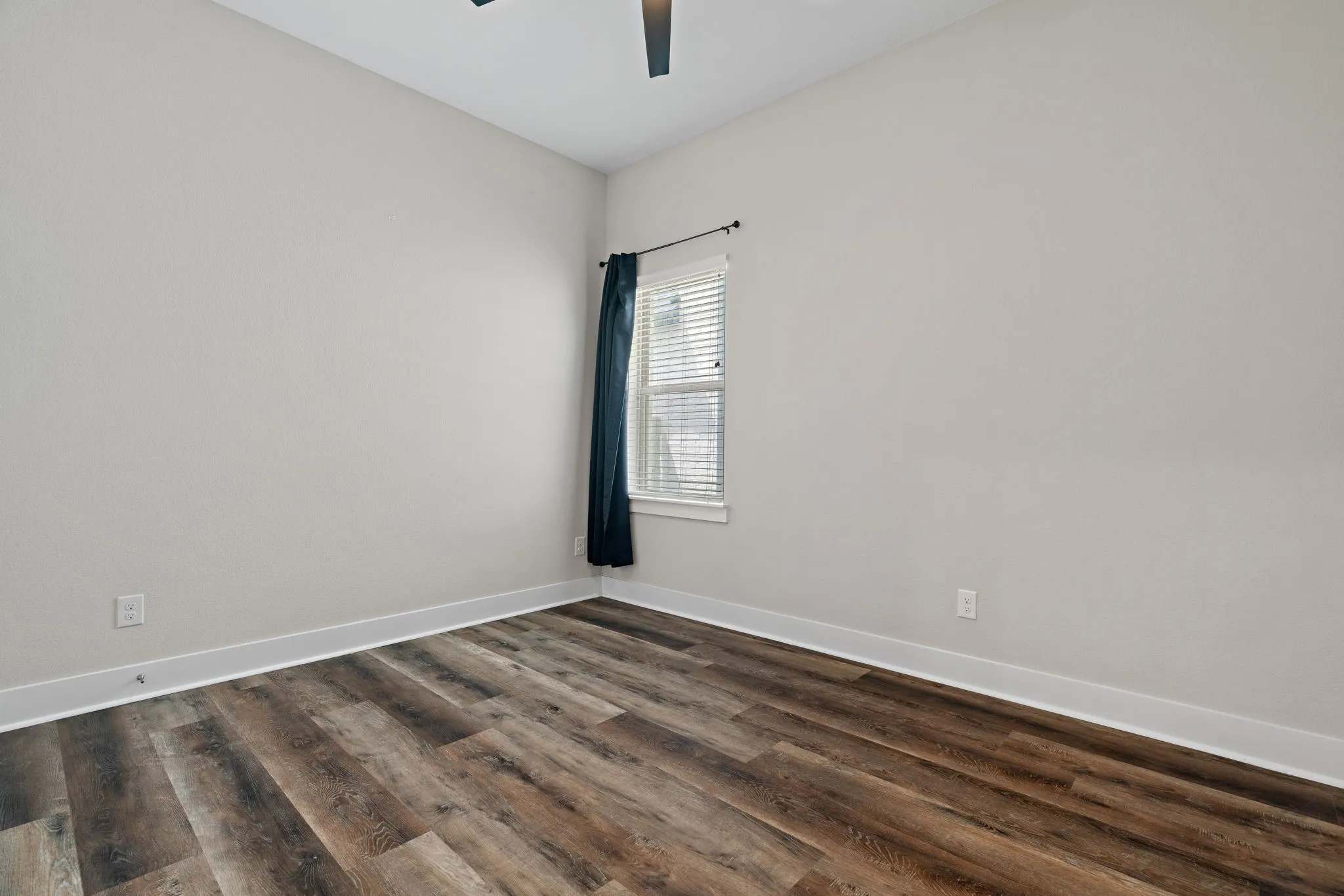Neutral wall color, wood-finish flooring, white window blinds, and a ceiling fan