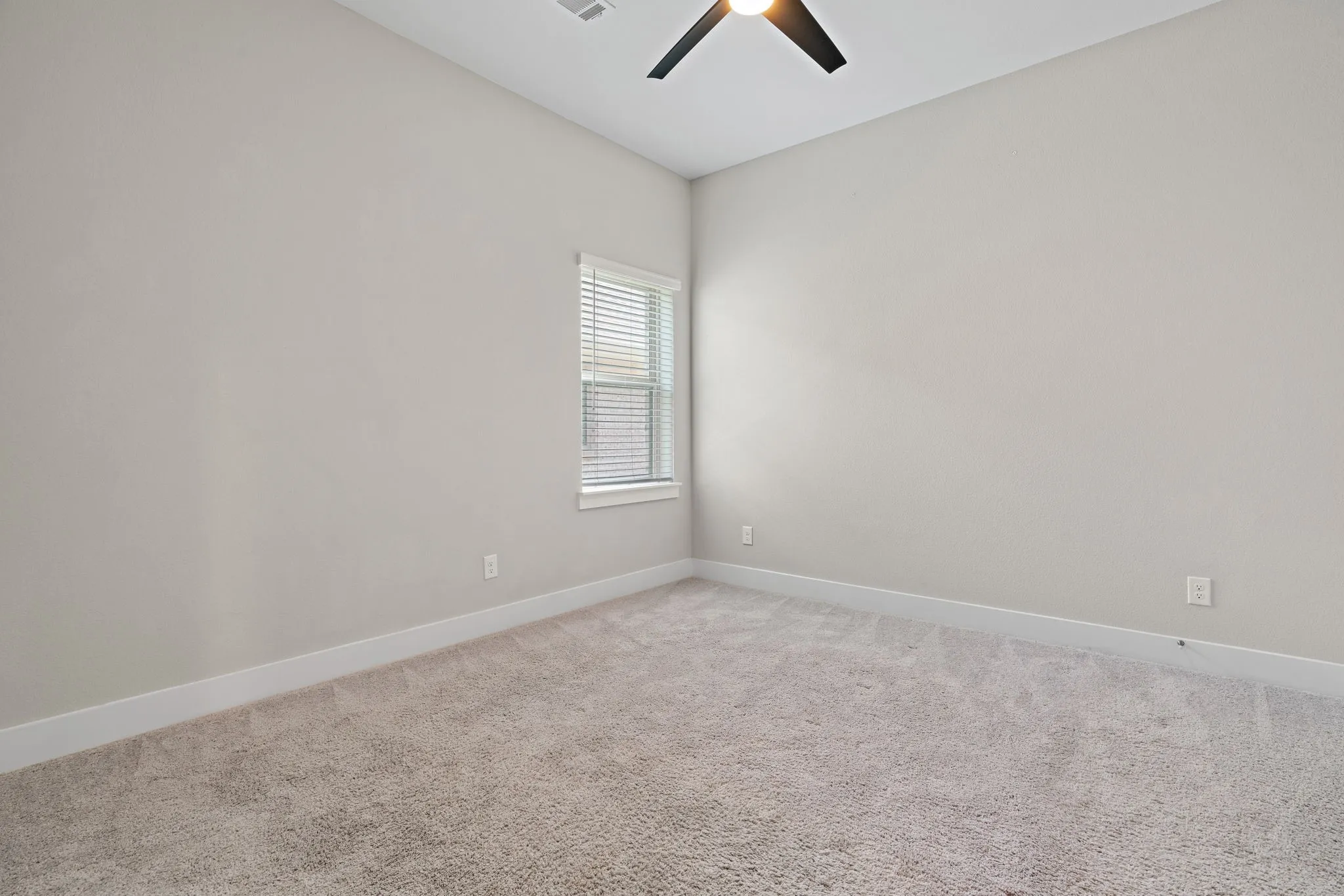 Carpeted room featuring a ceiling fan, a window with blinds, light gray walls, and white baseboards