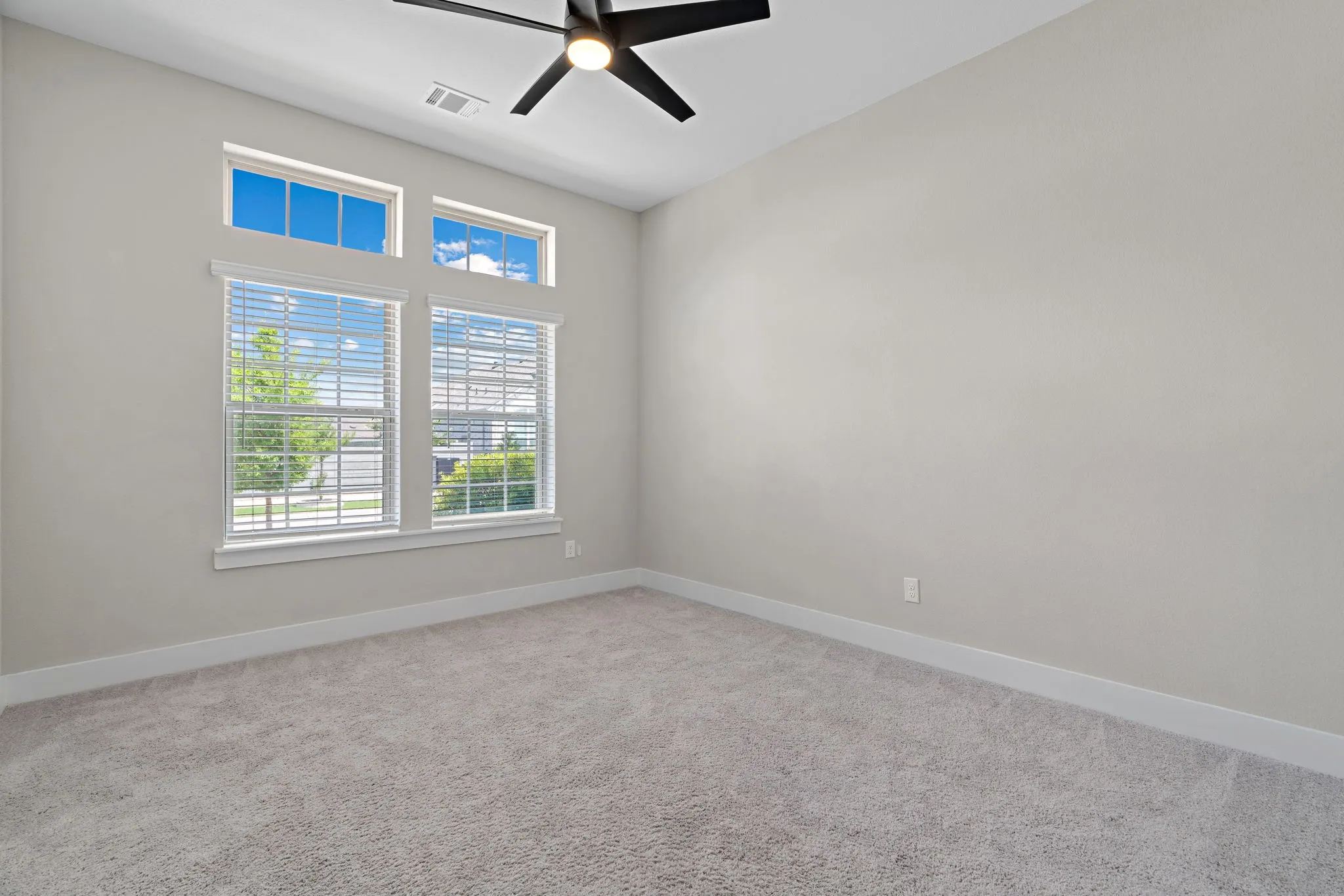 Neutral-toned room featuring a large window array with horizontal blinds and clerestory windows