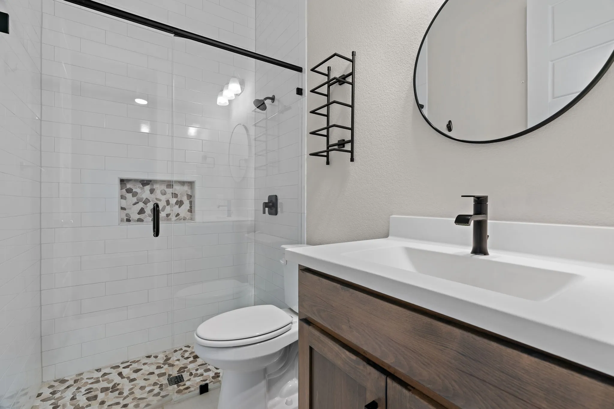 Contemporary bathroom featuring a walk-in shower with white subway tile, a pebble-finish shower floor, and a recessed niche