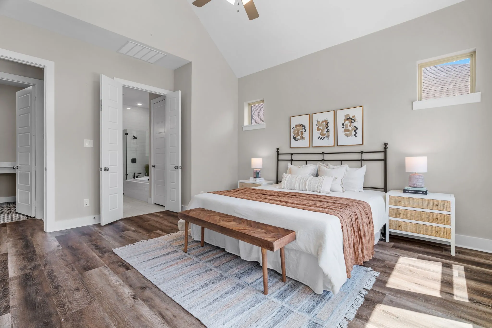 Bedroom featuring vaulted ceilings, wood-finish flooring, two upper windows, and a ceiling fan