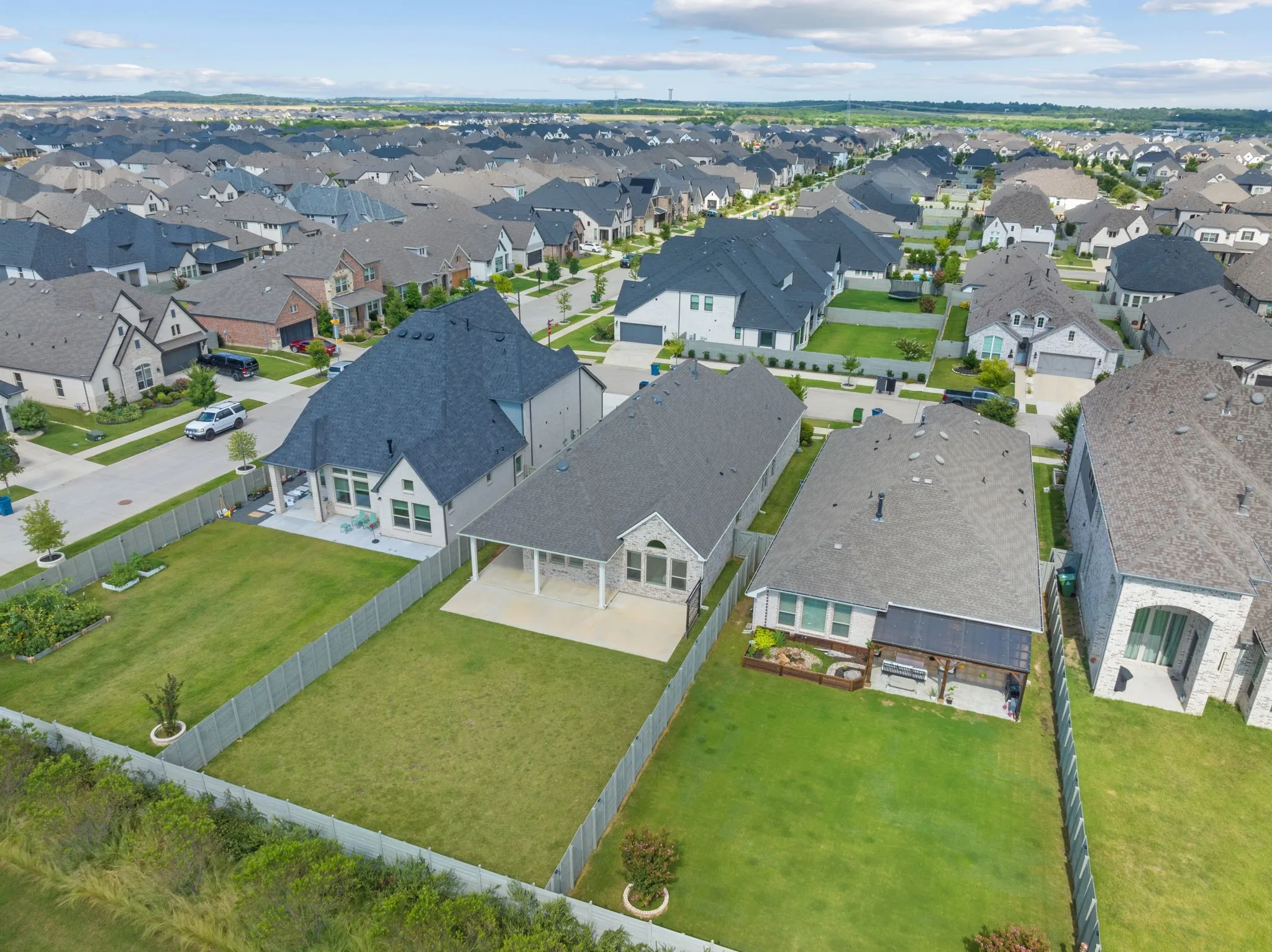 Aerial perspective showcasing a residential neighborhood with uniformly designed homes featuring dark gray shingle roofs