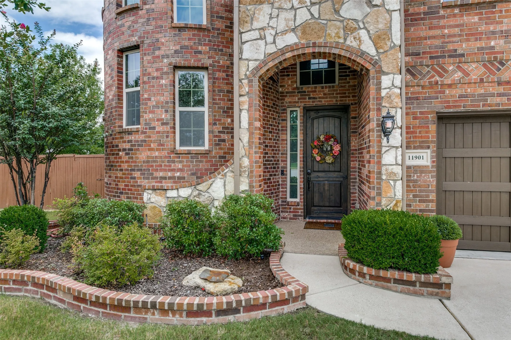 Brick and stone facade featuring an arched entryway with a dark wood door