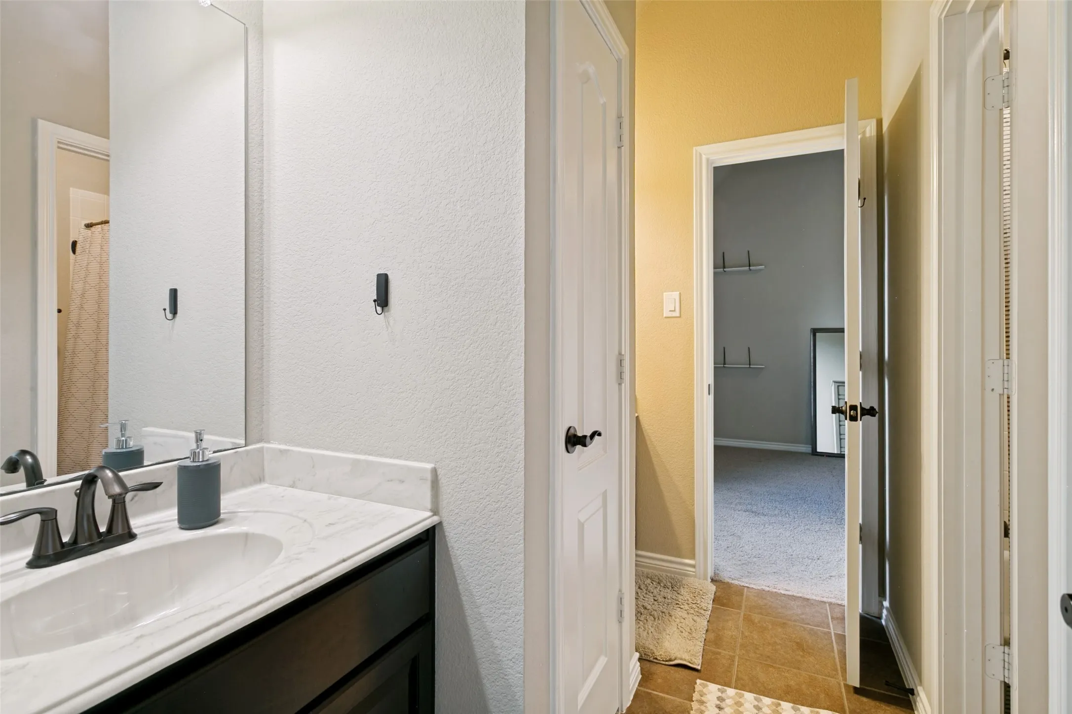 Modern Jack and Jill  bathroom featuring a dark-finished vanity with a white sink, quartz countertop, and matte faucet