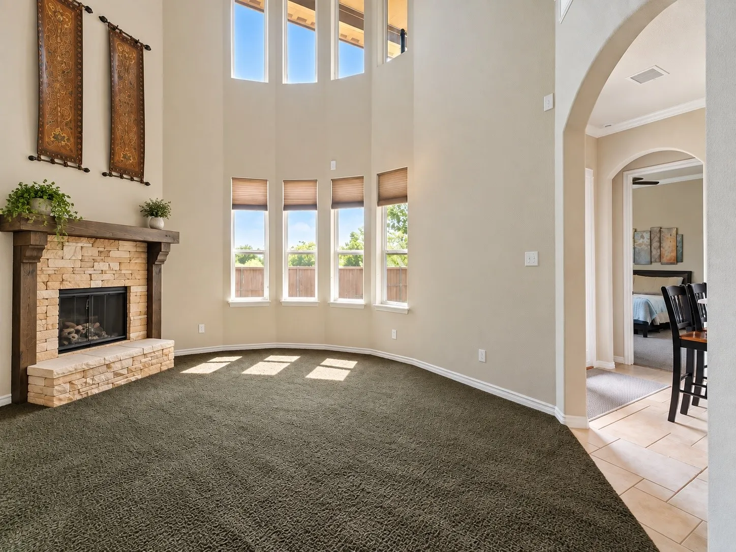 Two-story living area with a stone-clad fireplace featuring a wood mantel