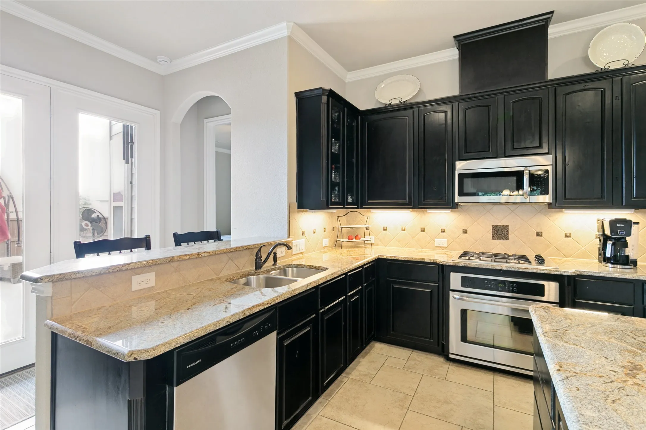 Elegant kitchen featuring dark cabinetry with stainless steel appliances, including a gas cooktop and built-in microwave