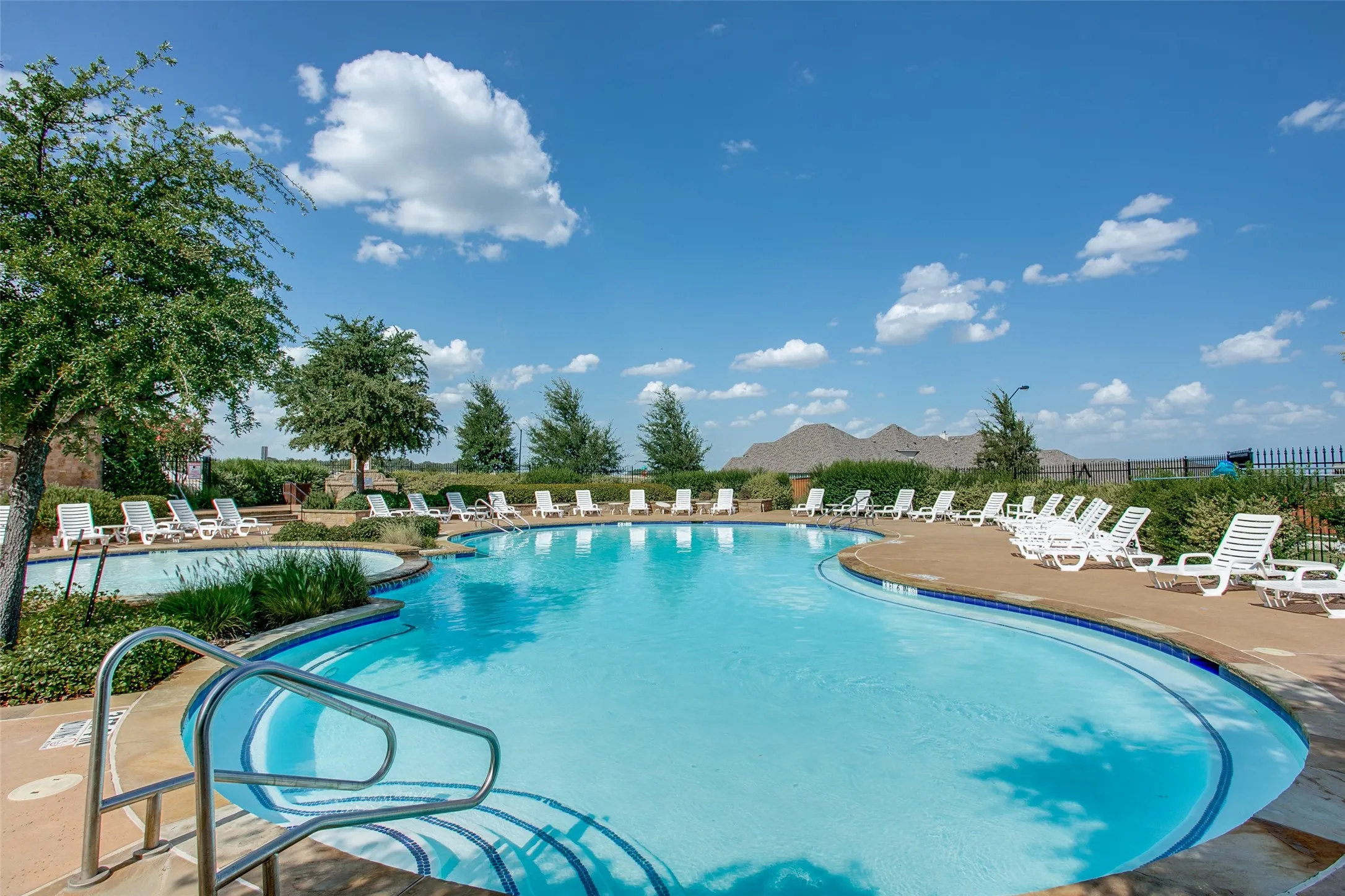 Community Resort-style swimming pool featuring a curved design, integrated spa, and surrounding hardscaping