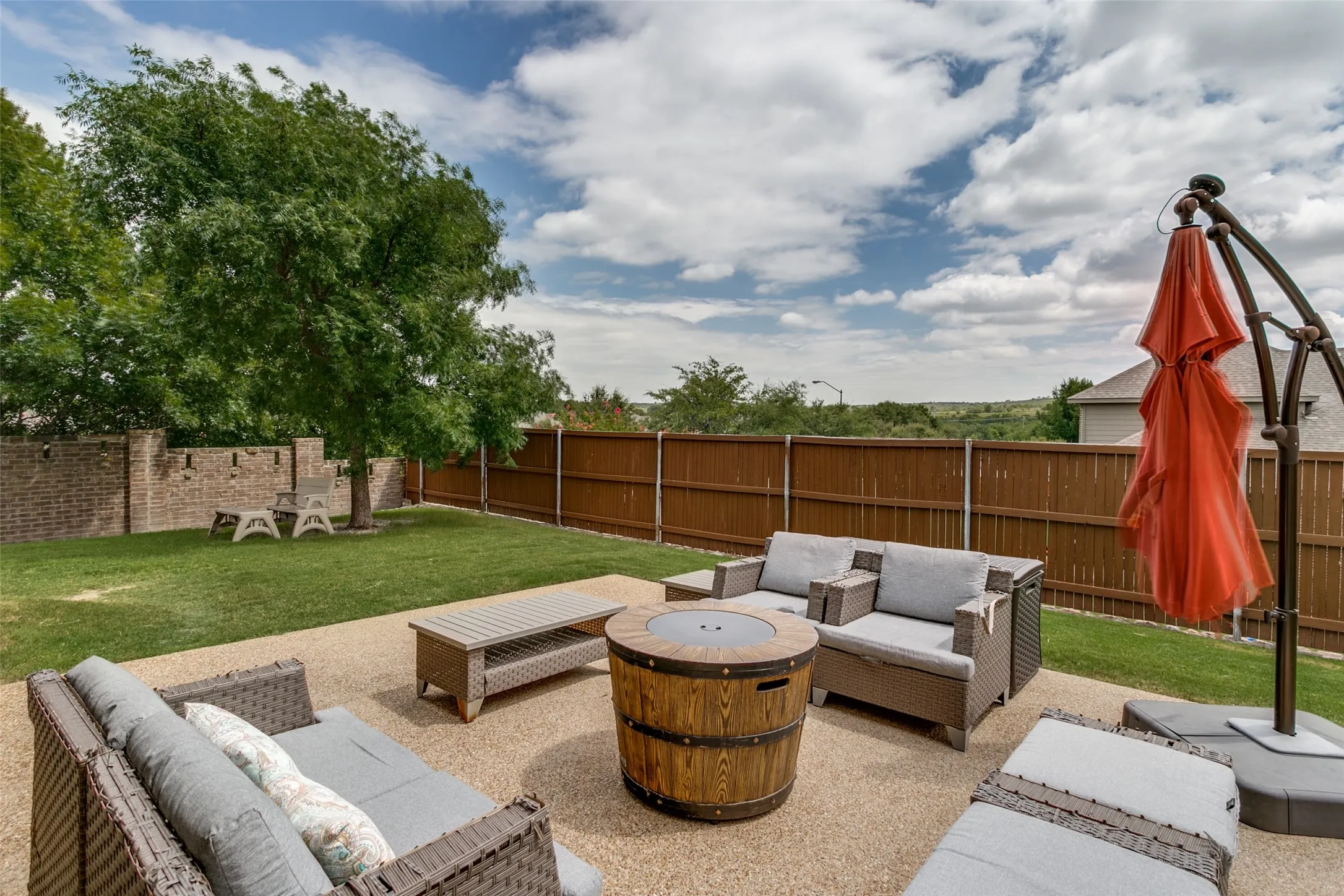 Spacious backyard featuring a large aggregate patio, expansive lawn, and mature trees