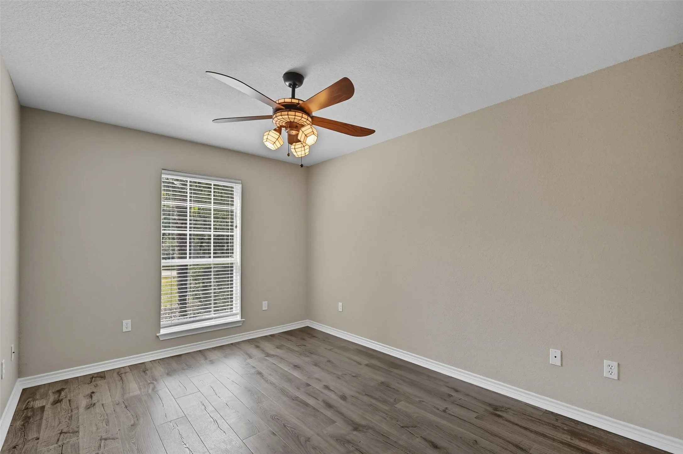 Bedroom featuring wood finished floors, a textured ceiling, and ceiling fan