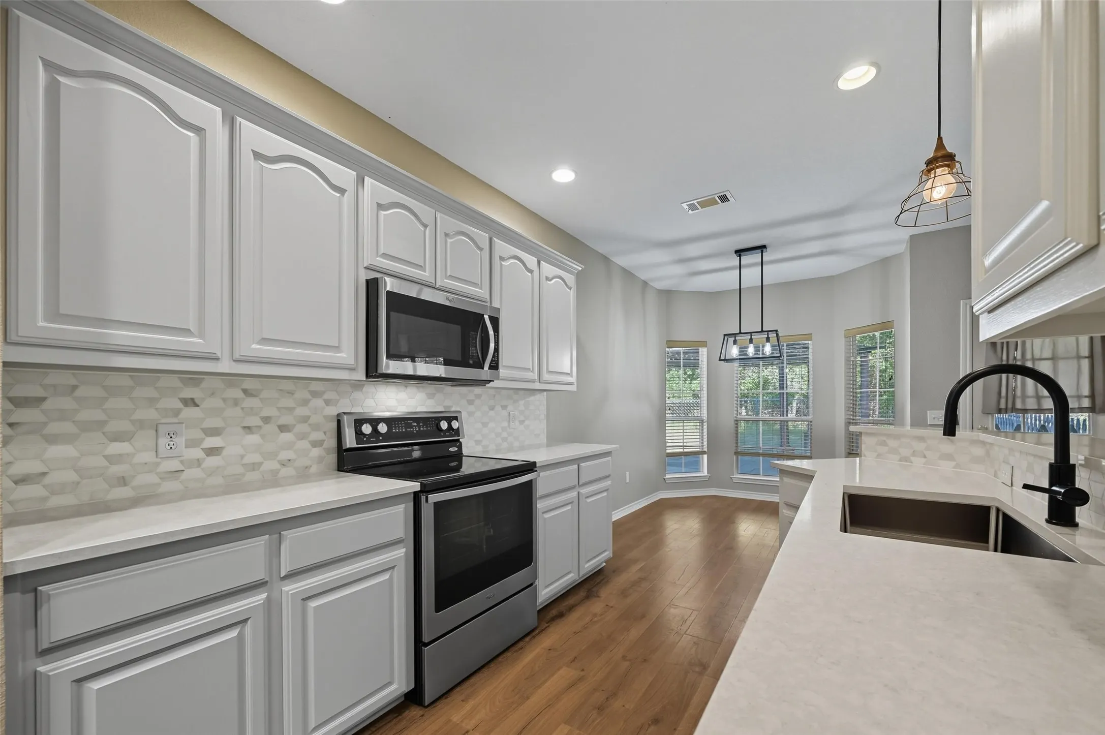 Kitchen with hanging light fixtures, stainless steel appliances, tasteful backsplash, dark wood-style floors, and recessed lighting