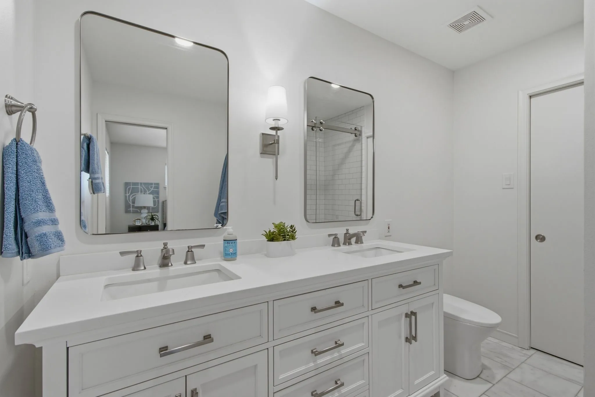 Dual vanity with integrated sinks, brushed nickel fixtures, and white cabinetry