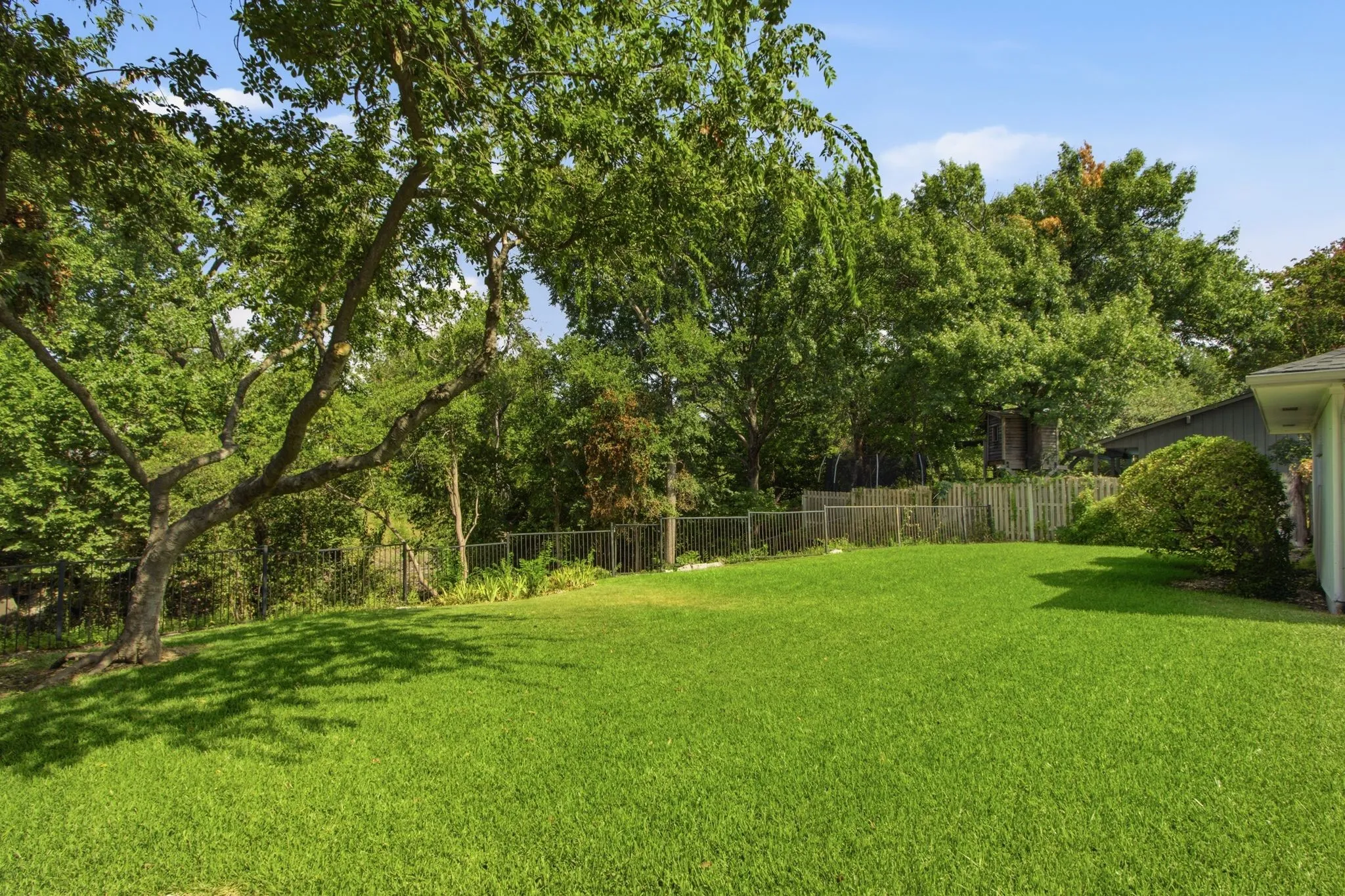 Expansive green lawn with mature trees providing natural shade
