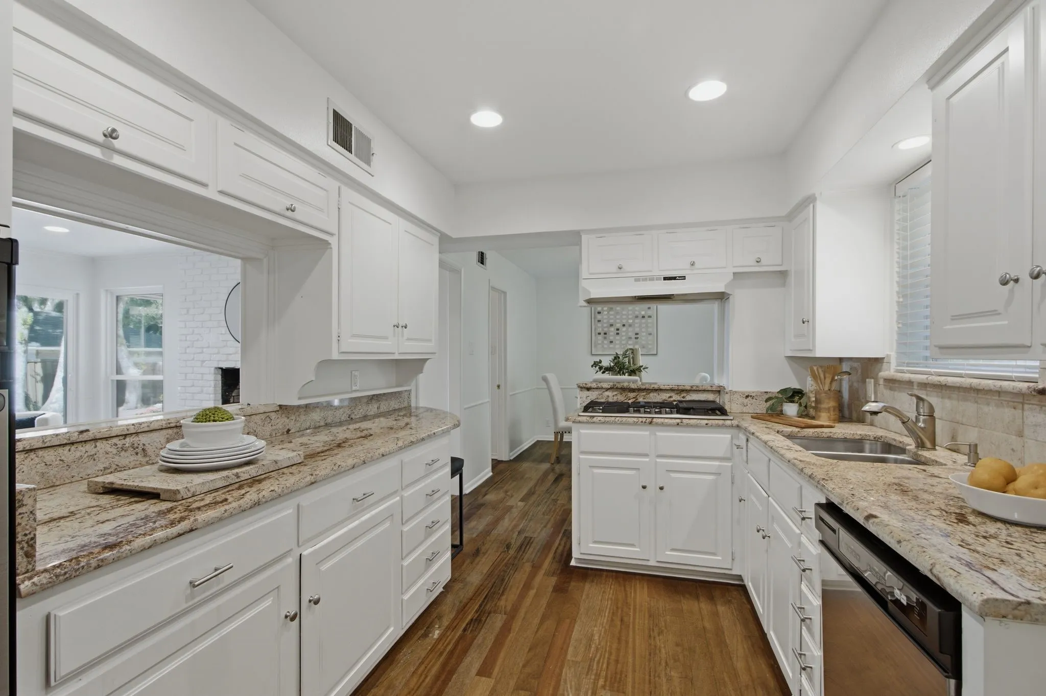 Kitchen featuring white cabinetry, granite countertops, wood-finish flooring, recessed lighting, and a pass-through window