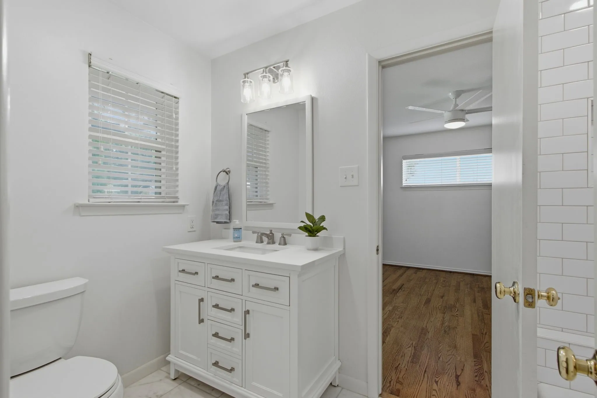White bathroom vanity with brushed nickel hardware, a white countertop, and an undermount sink