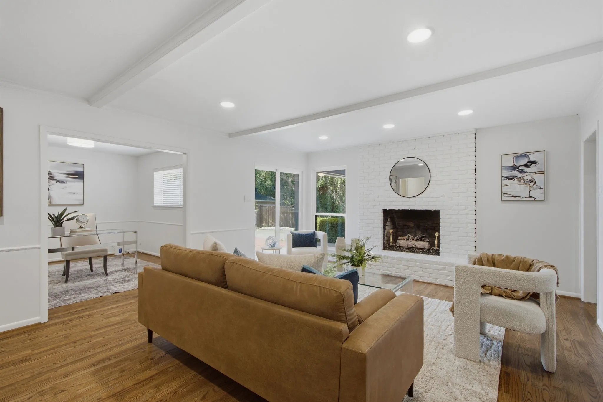 Bright living space featuring wood-finish flooring, a painted brick fireplace, and recessed lighting