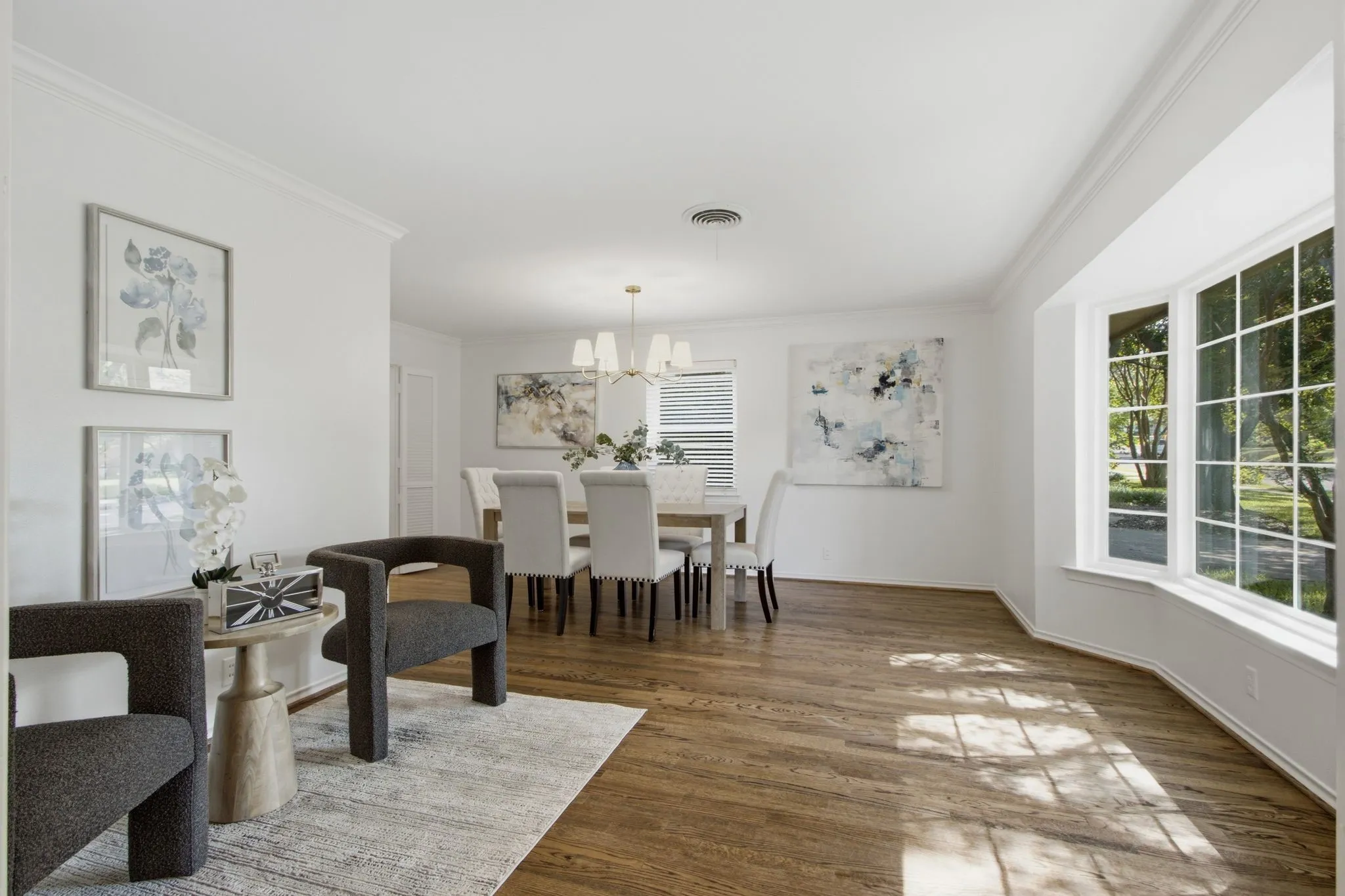 Spacious interior with rich wood-finish flooring, white crown molding, and a bay window featuring grid-pattern panes