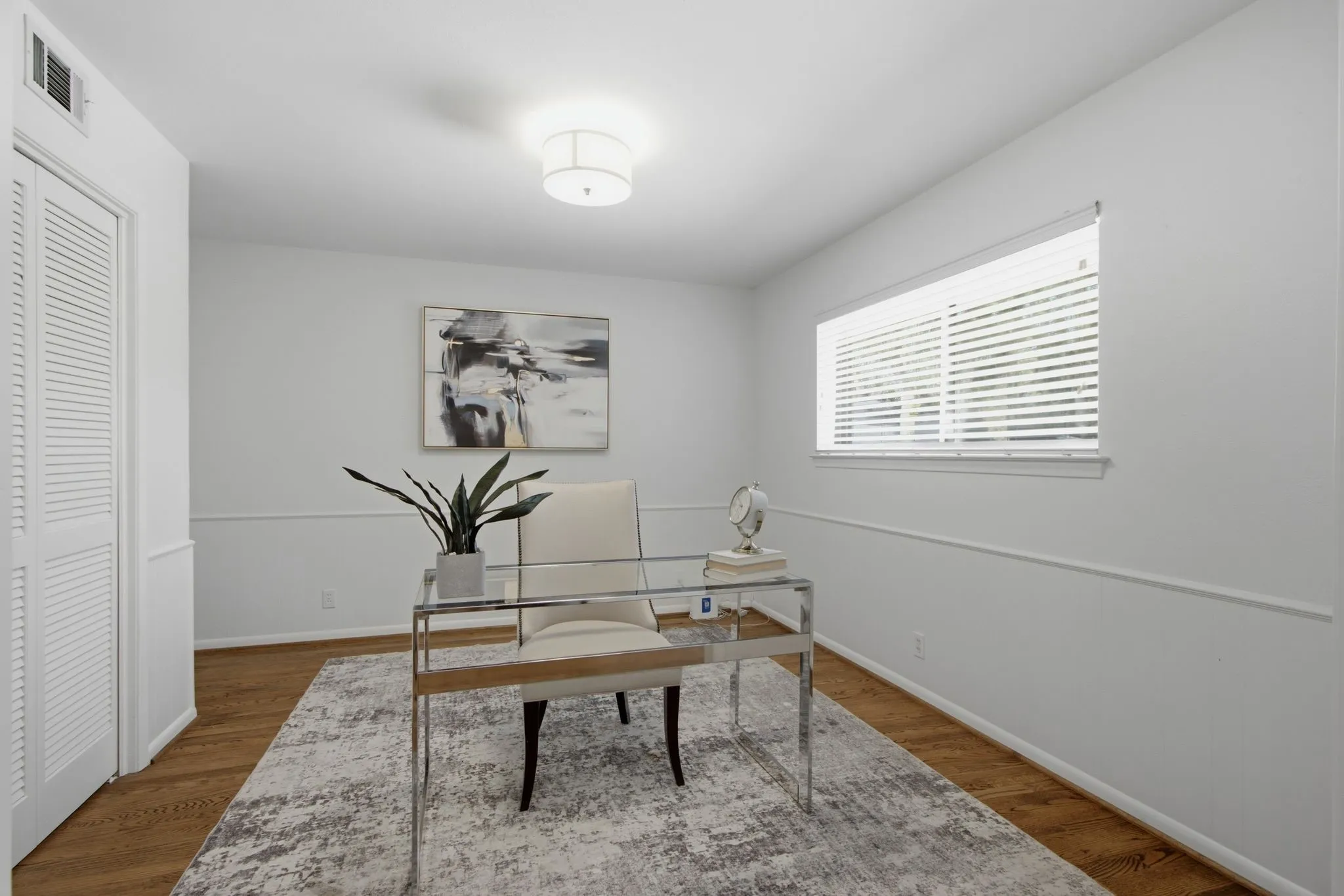 Bright room with wood-finish flooring, white walls, and a single window with horizontal blinds