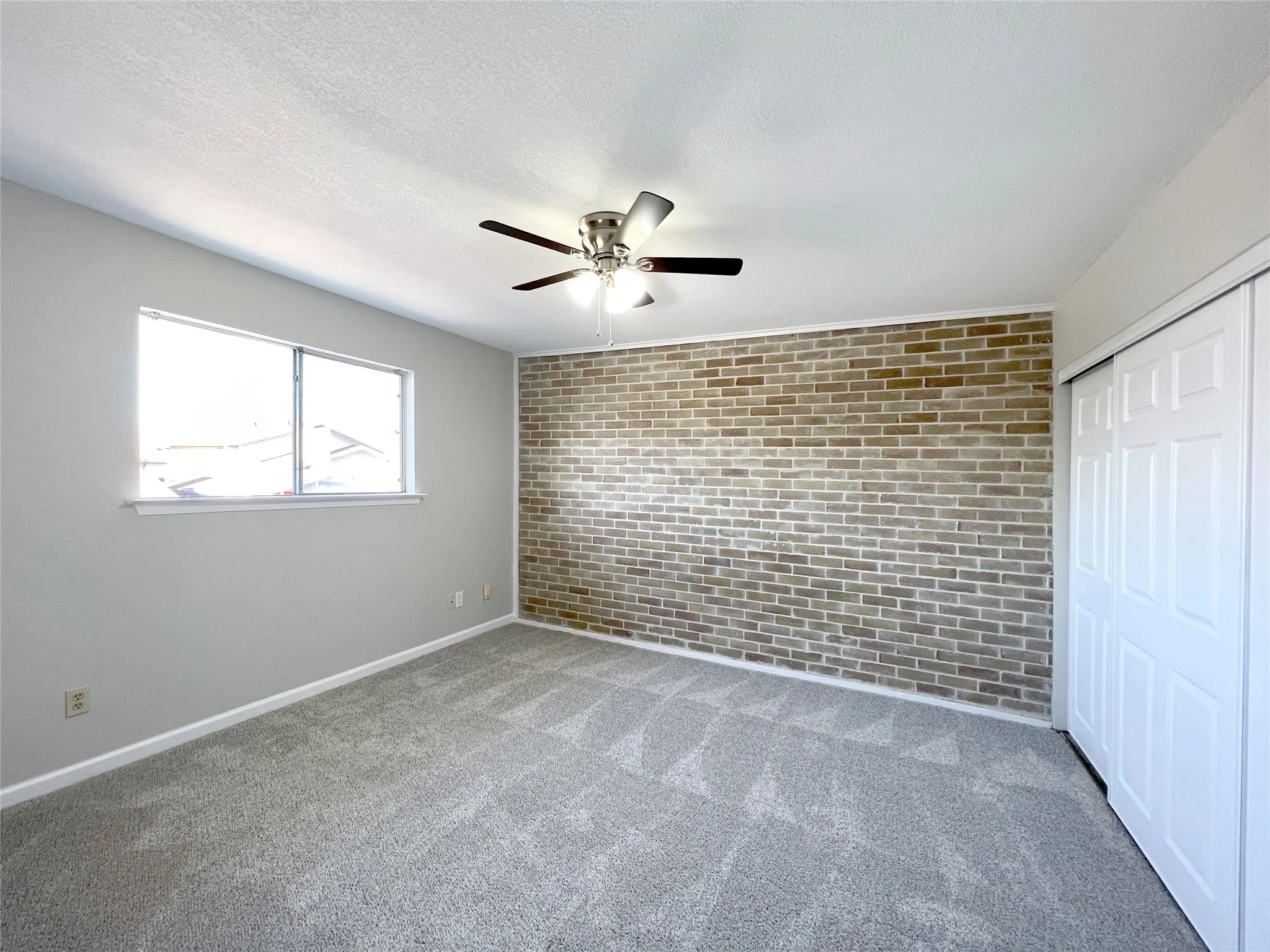 Primary bedroom with wall of closets and brick accent wall